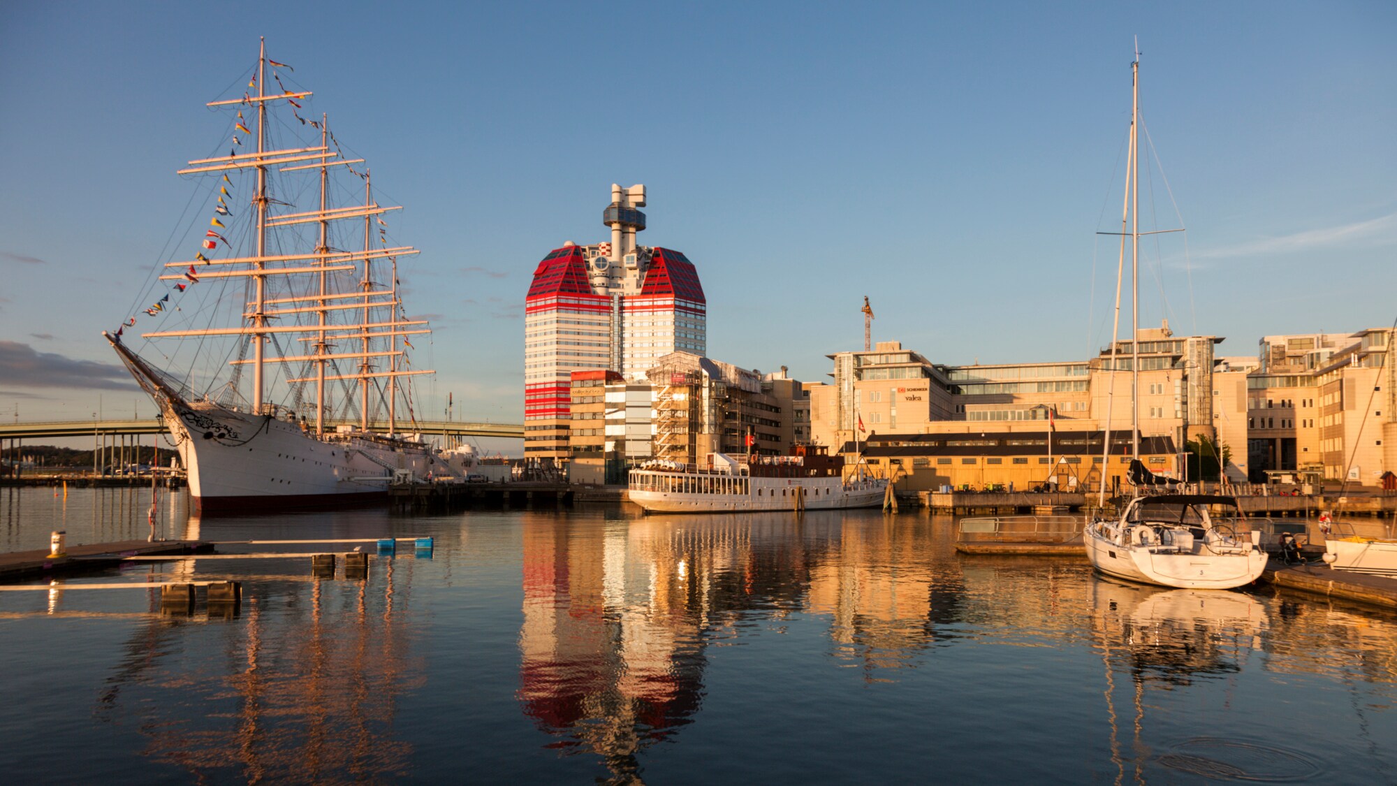 Anlagestelle im Hafen von Göteborg bei Sonnenuntergang mit verschiedenen Schiffen und dem Skanskaskrapan-Hochhaus im Hintergrund. Anlagestelle im Hafen von Göteborg bei Sonnenuntergang mit verschiedenen Schiffen und dem Skanskaskrapan-Hochhaus im Hintergrund.