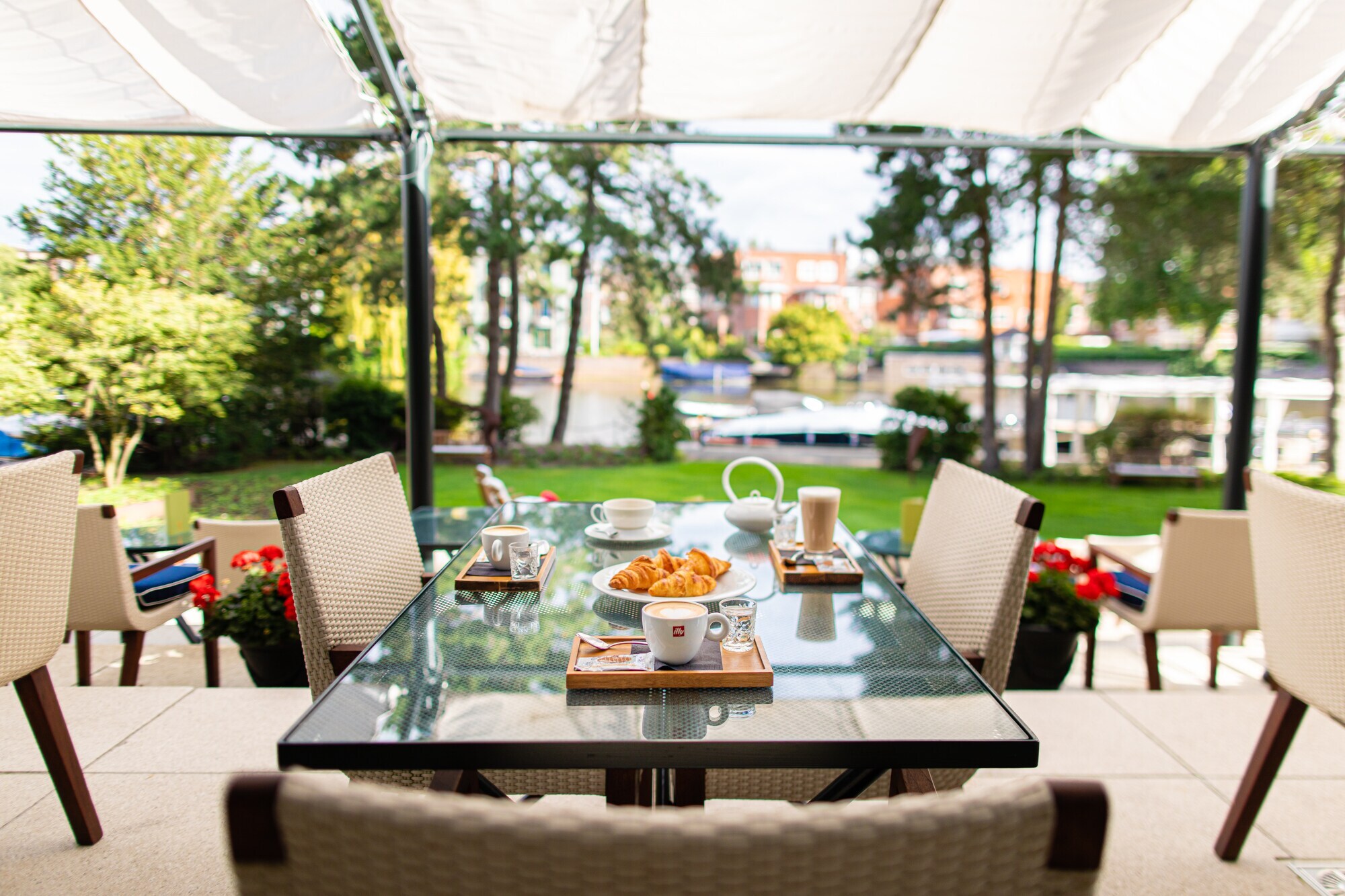 Frühstück auf einem Tisch auf einer Hotelterrasse an einem Kanal.
