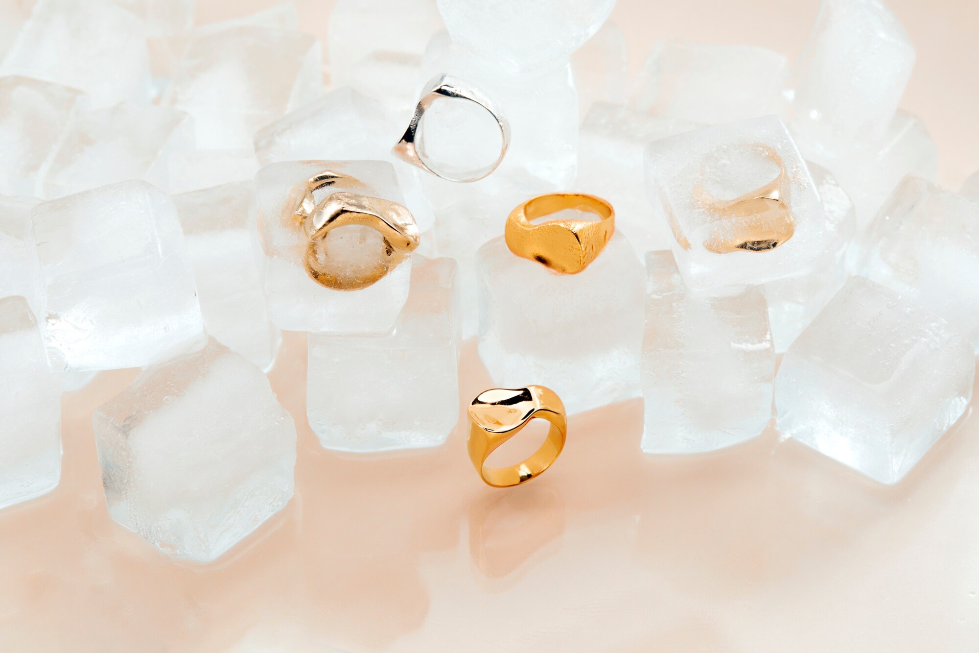 Mehrere Gold- und Silberringe auf und in Eiswürfeln Mehrere Gold- und Silberringe auf und in Eiswürfeln