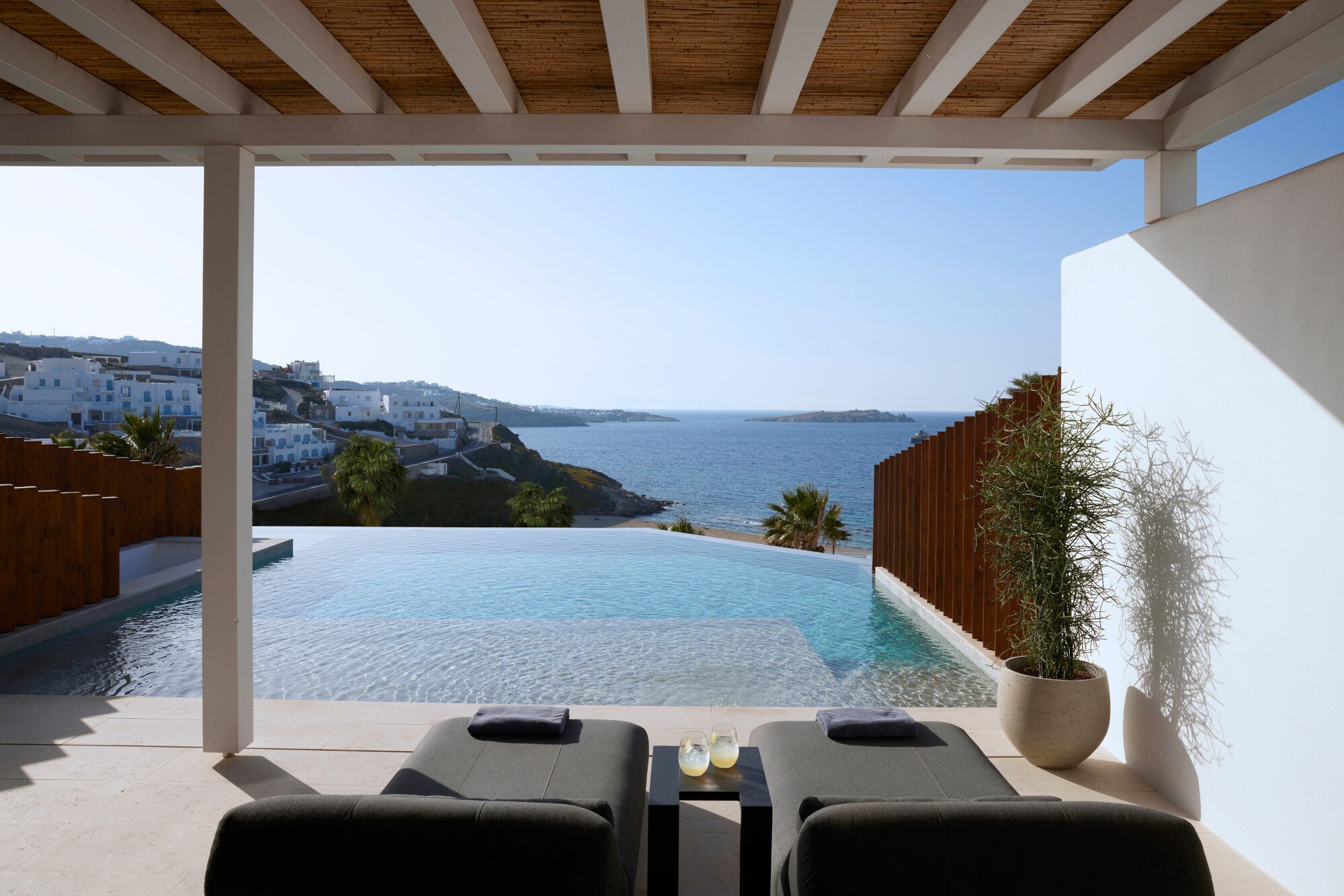 Terrasse mit Liegen und Infinitypool mit Meerblick an einem Küstenort.