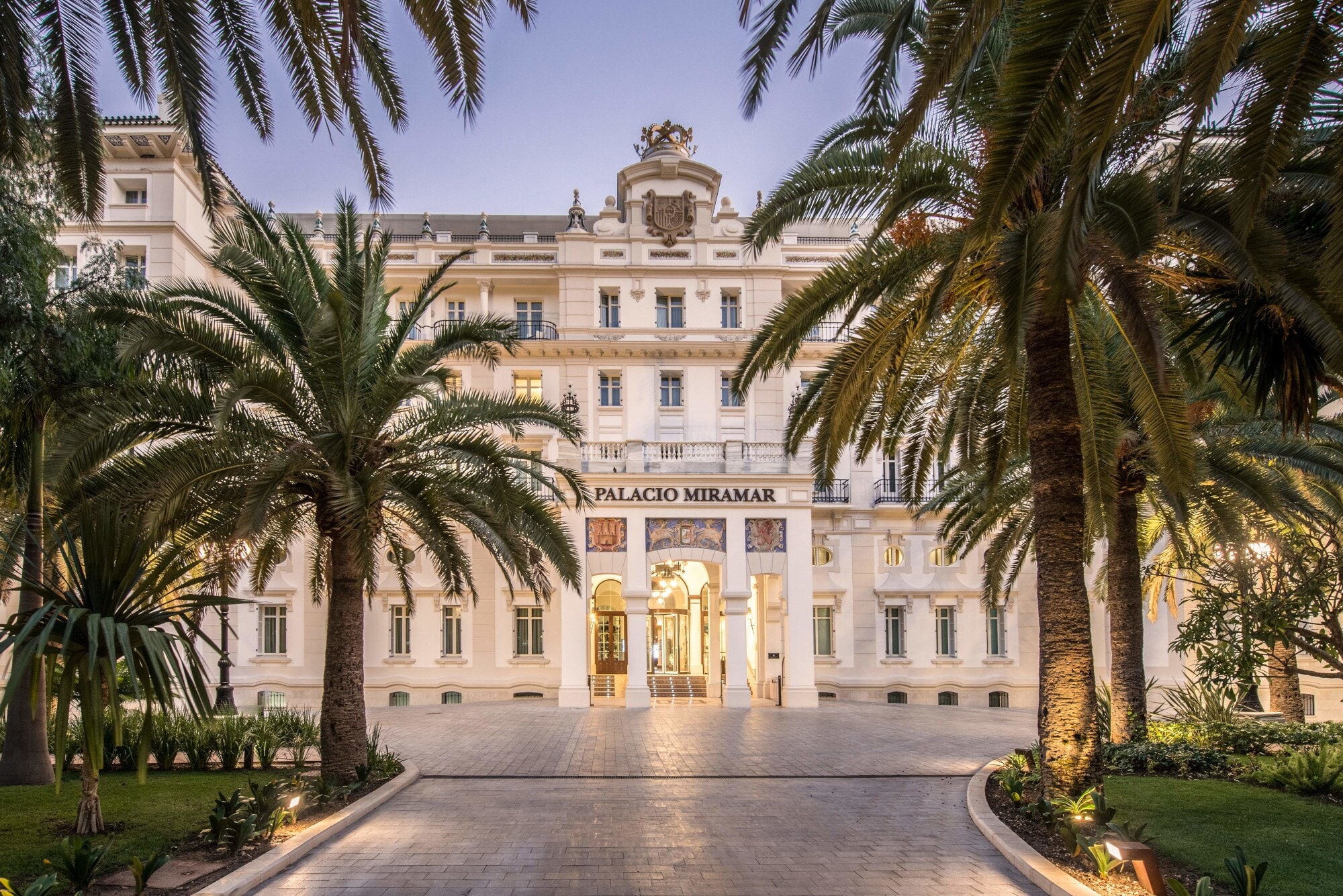 Imposante, helle Frontfassade eines Grandhotels mit Vorplatz, im Vordergrund Begrünung mit Palmen. Imposante, helle Frontfassade eines Grandhotels mit Vorplatz, im Vordergrund Begrünung mit Palmen.