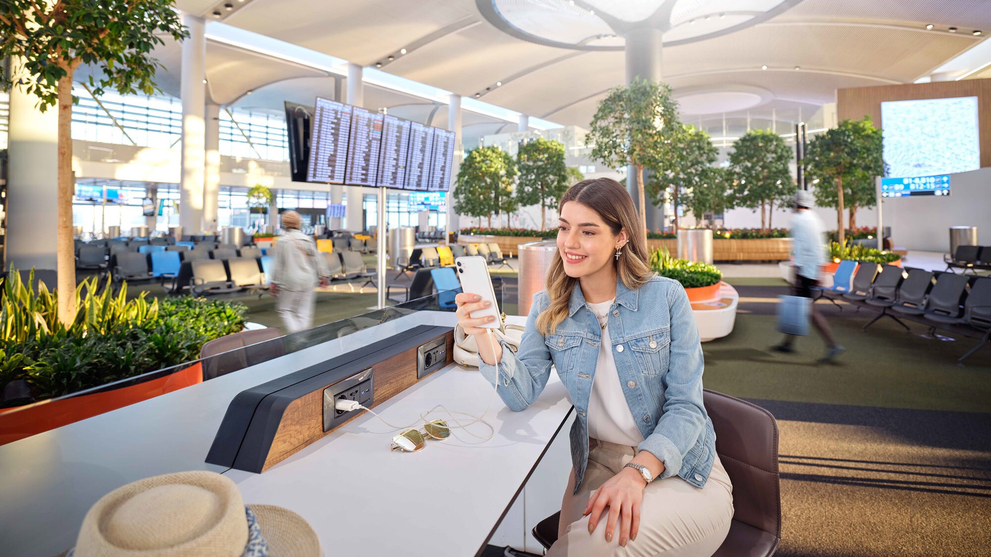 Eine junge Frau mit Smartphone sitzt in einem Wartebereich am Flughafen. Eine junge Frau mit Smartphone sitzt in einem Wartebereich am Flughafen.