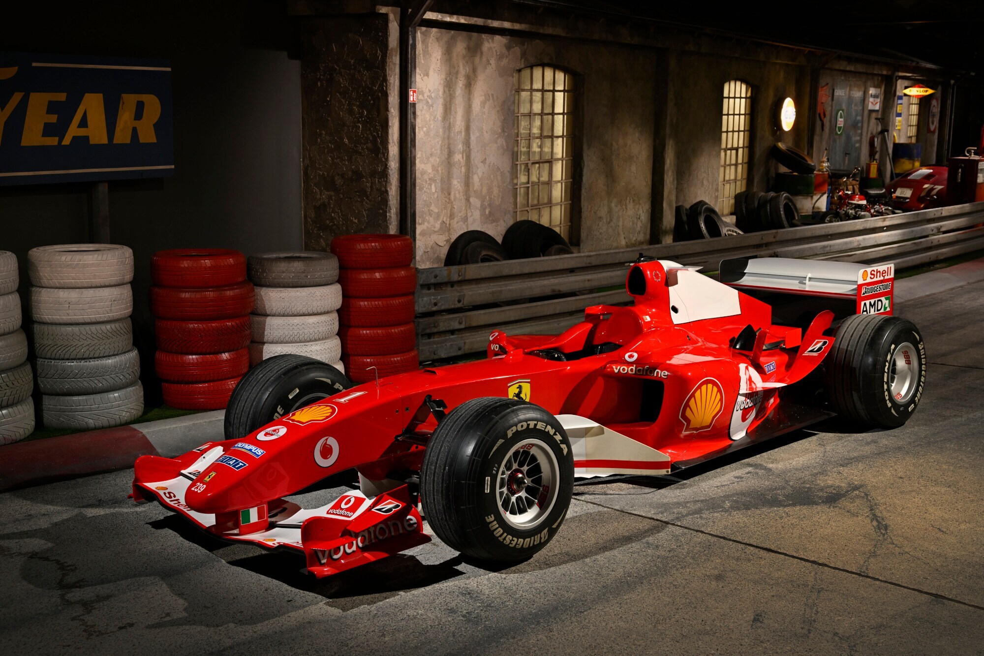 Ein roter Ferrari-Rennwagen auf einer nachgebildeten Rennstrecke in einer Ausstellung.
