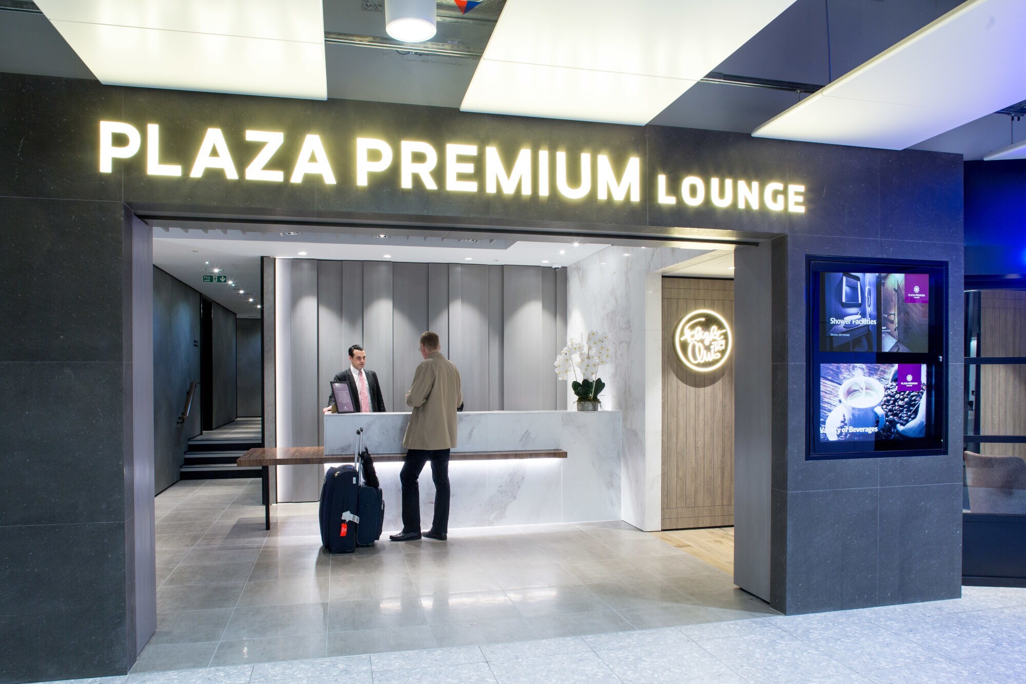 Ein Mann mit Gepäck beim Check-in am Eingang einer Plaza Premium Flughafen-Lounge.