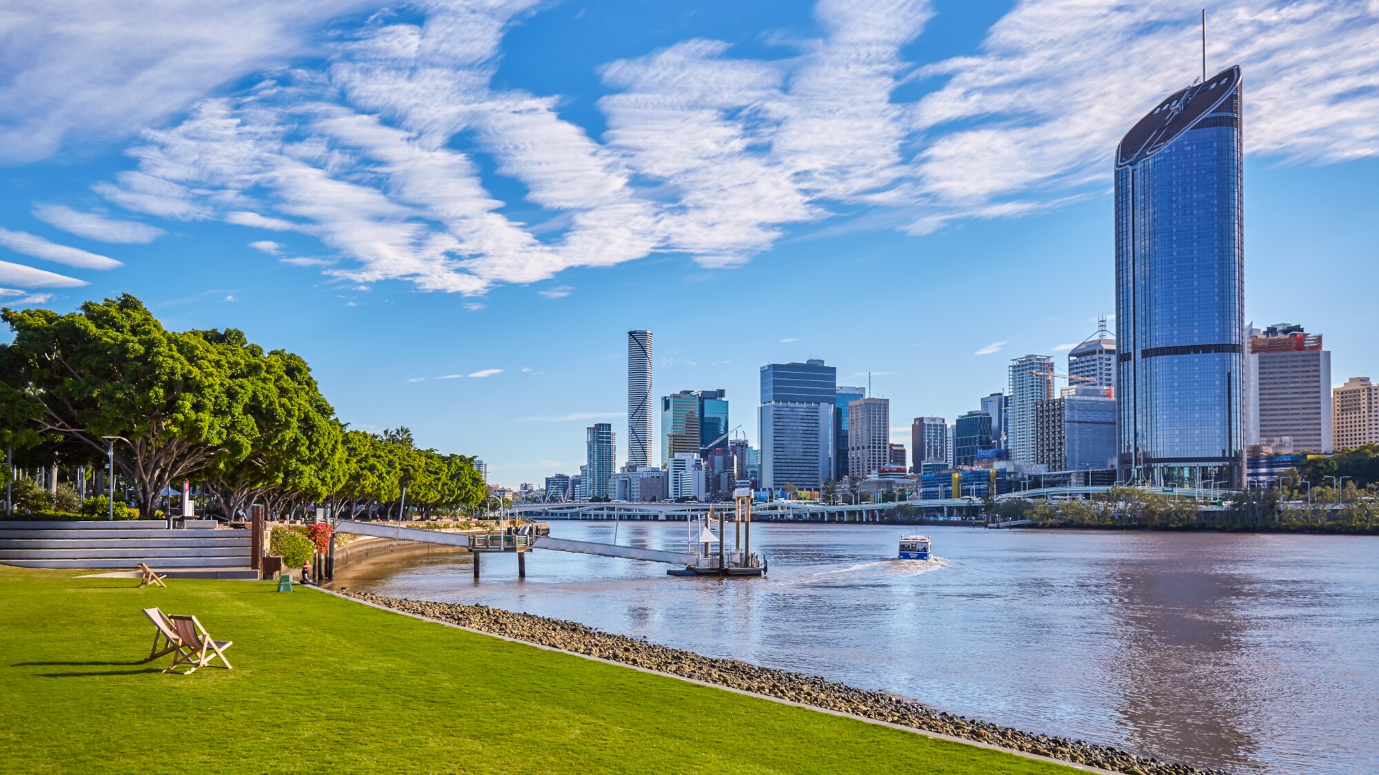 Grünfläche mit Liegestühlen am Brisbane River vor der Skyline der Stadt. Grünfläche mit Liegestühlen am Brisbane River vor der Skyline der Stadt.