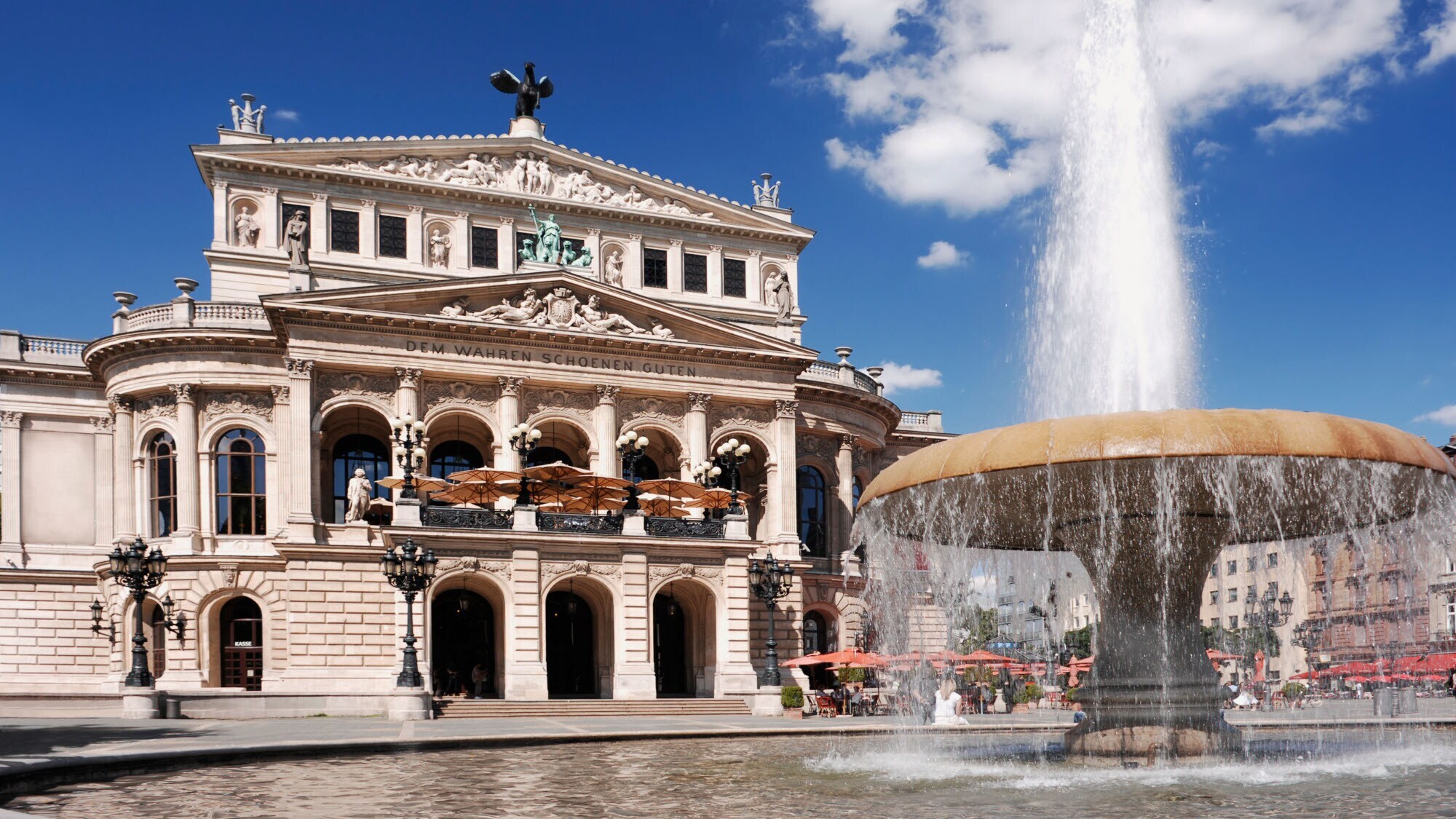 Prachtvolles Operngebäude im Stil der Neorenaissance mit Restaurant, im Vordergrund ein Springbrunnen.