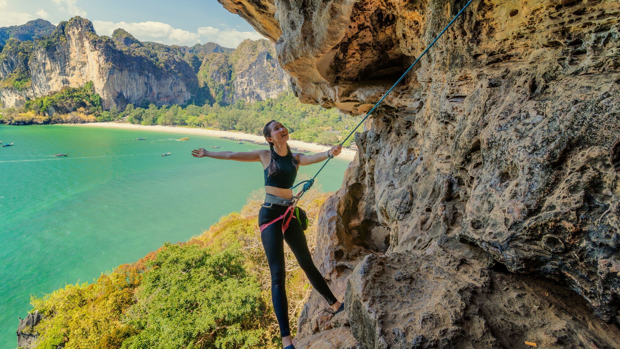 Eine Freeclimberin an einem Felsen vor Strandpanorama. Eine Freeclimberin an einem Felsen vor Strandpanorama.