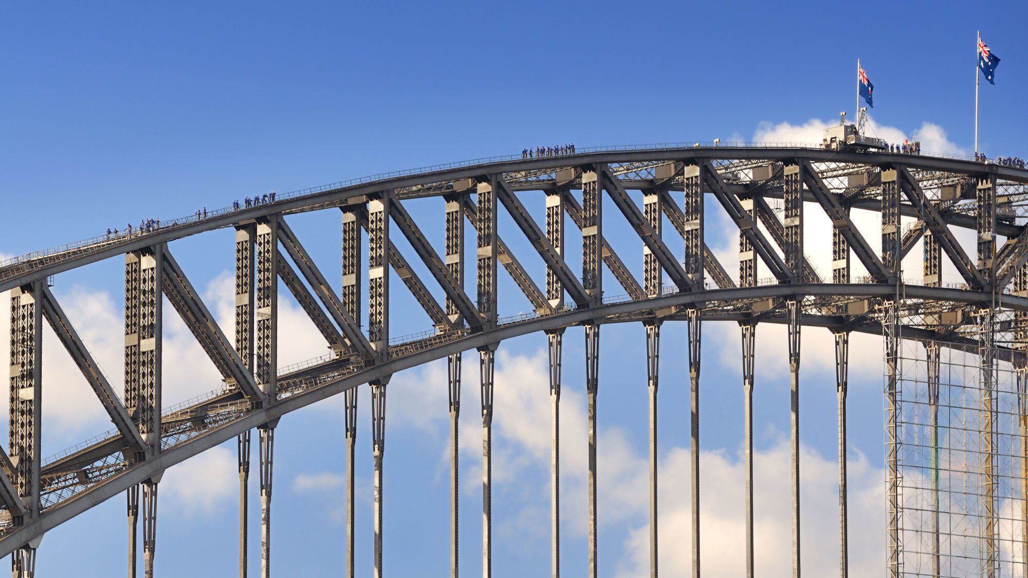 Personen auf einem Brückenbogen aus Stahl.