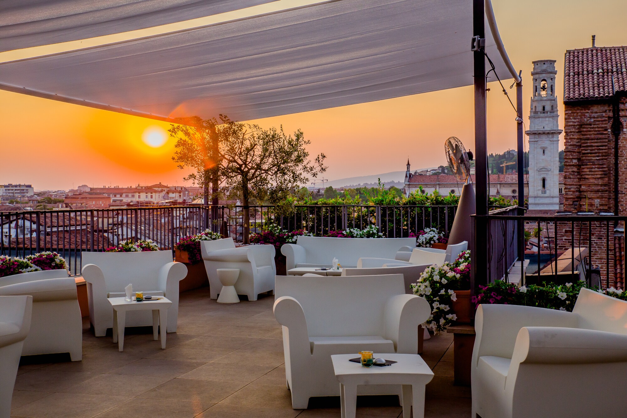 Dachterrasse mit weißen Sitzmöbeln in urbaner, mediterraner Umgebung bei Sonnenuntergang. Dachterrasse mit weißen Sitzmöbeln in urbaner, mediterraner Umgebung bei Sonnenuntergang.