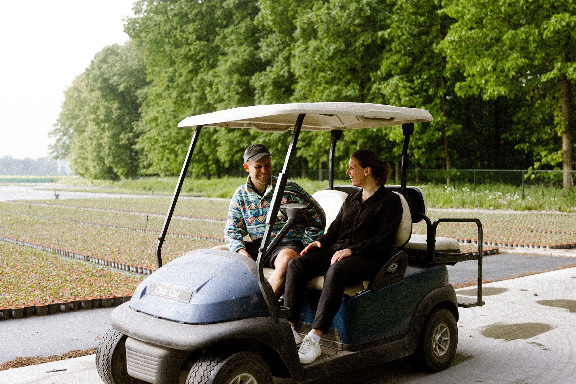 Die Gründerin Antonia Cox sitzt mit Benjamin Diedering in einem Golfplatzfahrzeug und stellt ihm ihr grünes Start-up vor