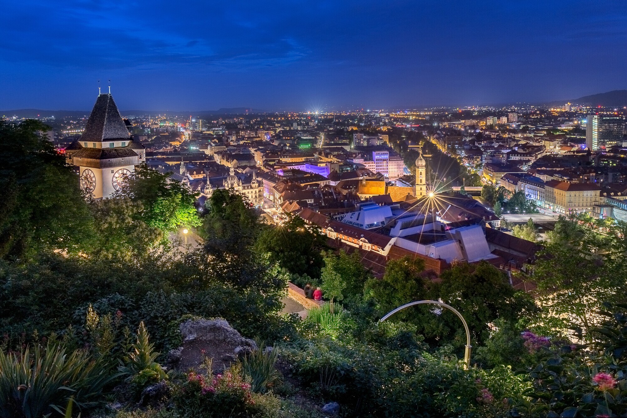 Panoramablick auf Graz von einem begrünten Berg mit Uhrenturm bei Nacht. Panoramablick auf Graz von einem begrünten Berg mit Uhrenturm bei Nacht.