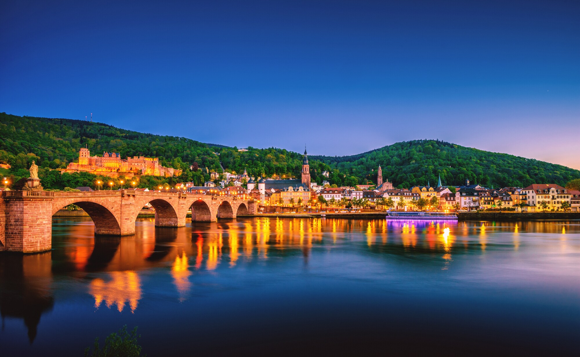 Blick auf die Heidelberger Skyline bei Nacht mit dem Neckar und der Alten Brücke im Vordergrund.