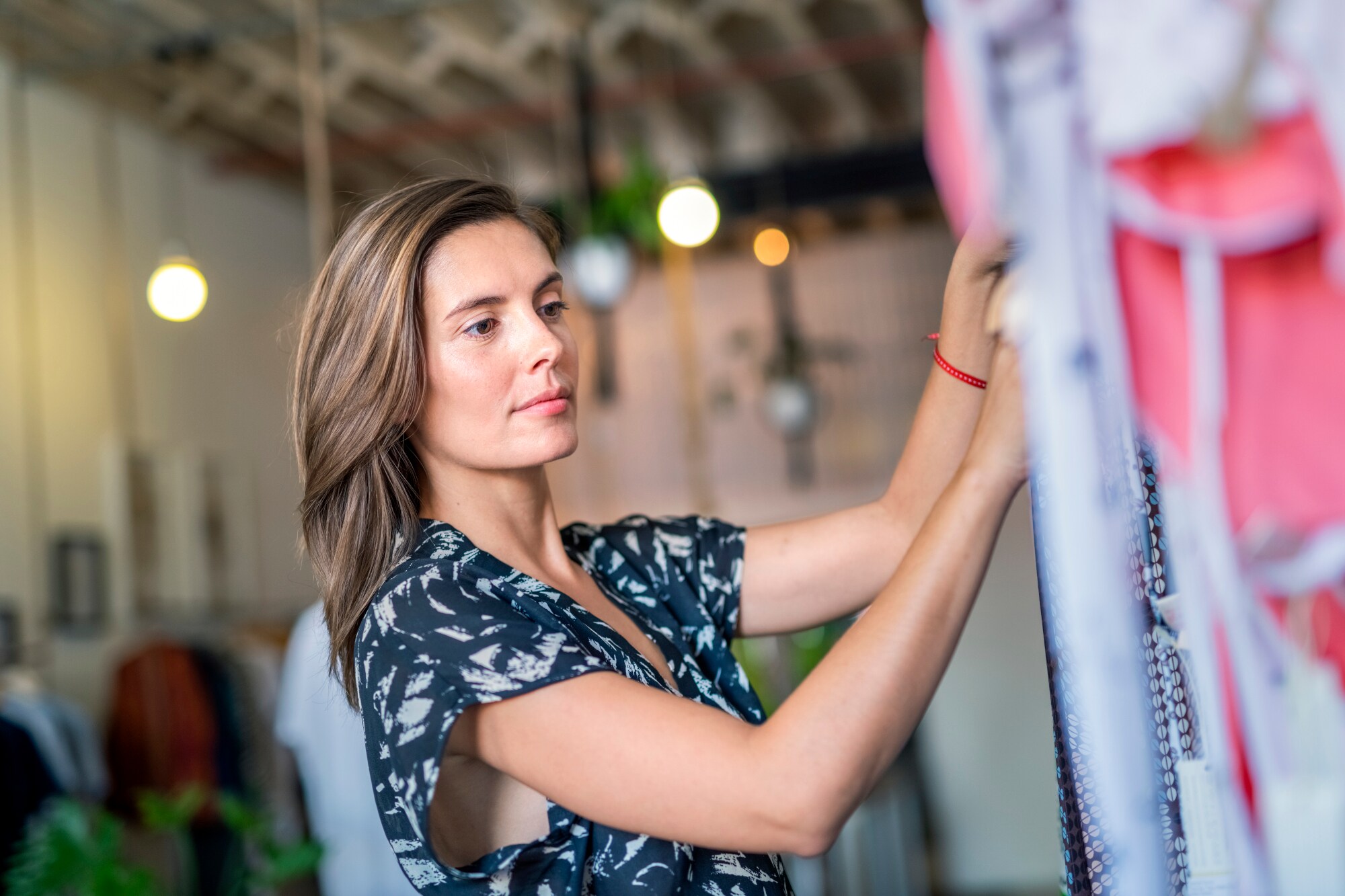 Eine Frau mittleren Alters sucht an einem Kleiderständer nach einem passenden Kleidungsstück.