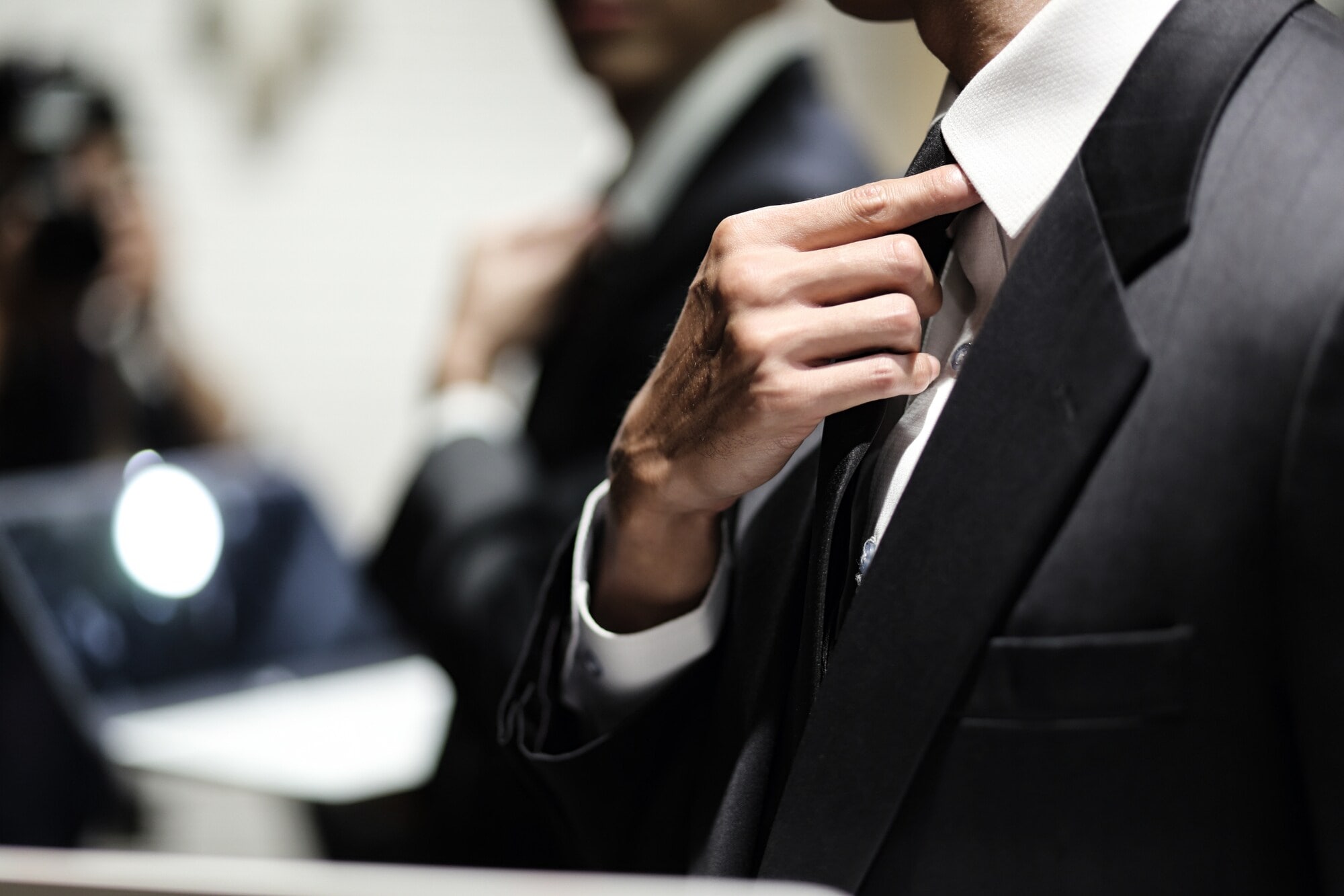 Nahaufnahme eines Mannes im Business-Anzug, der den Sitz seiner Krawatte korrigiert. Nahaufnahme eines Mannes im Business-Anzug, der den Sitz seiner Krawatte korrigiert.