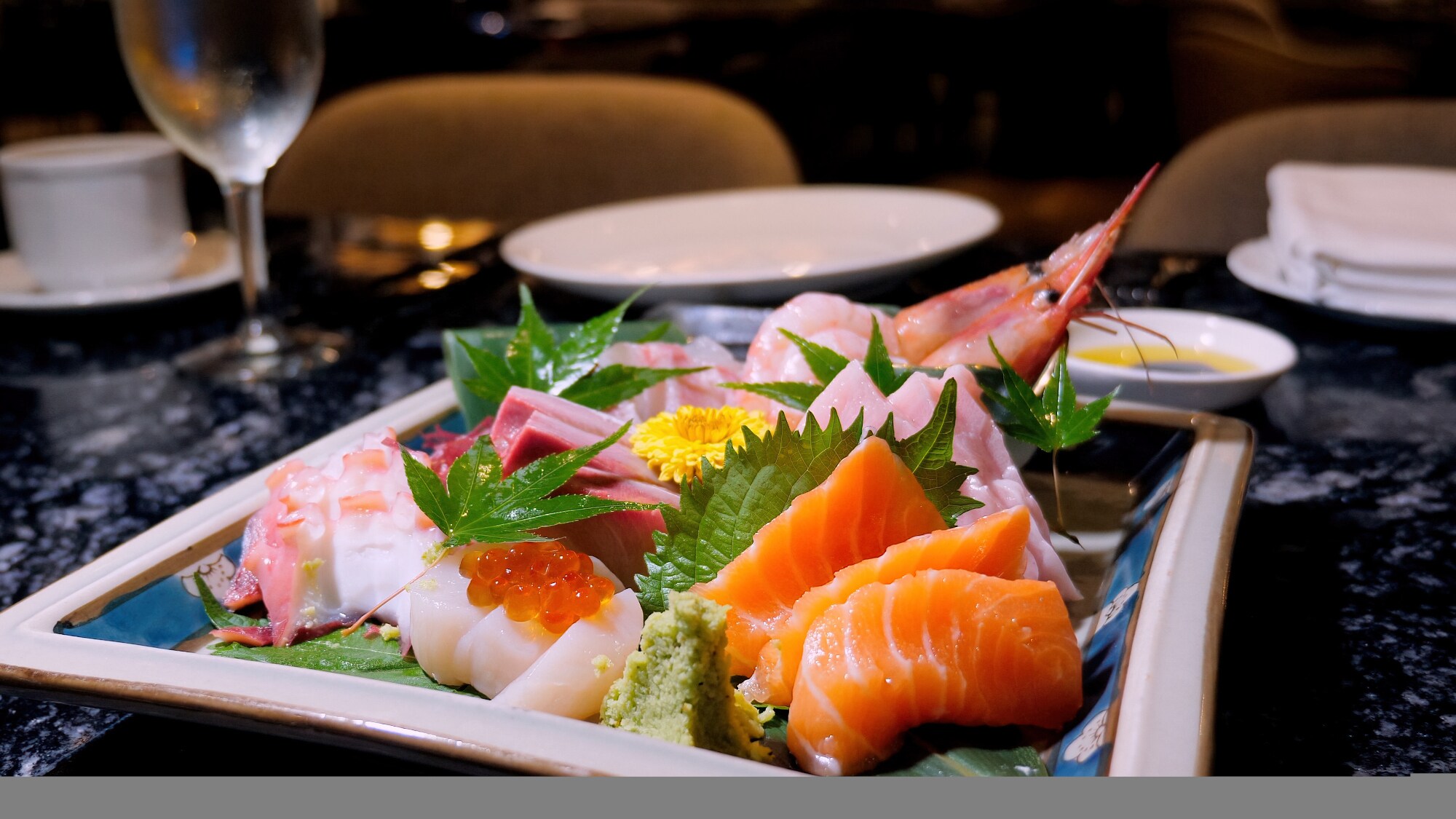 Verschiedene Sashimi Sushi und Scampi auf einem dekorierten Teller in einem Restaurant.
