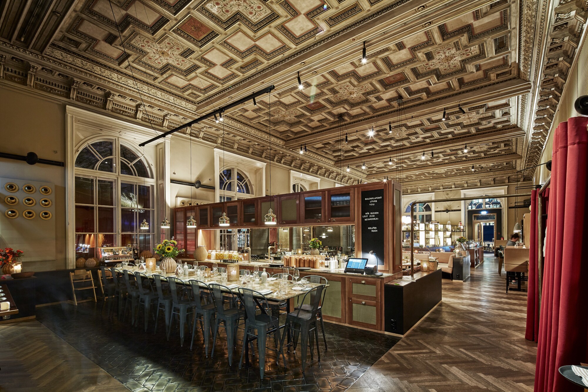 Restaurant mit einem langen, gedeckten Tisch, hohen Fenstern und Kassettendecke. Restaurant mit einem langen, gedeckten Tisch, hohen Fenstern und Kassettendecke.