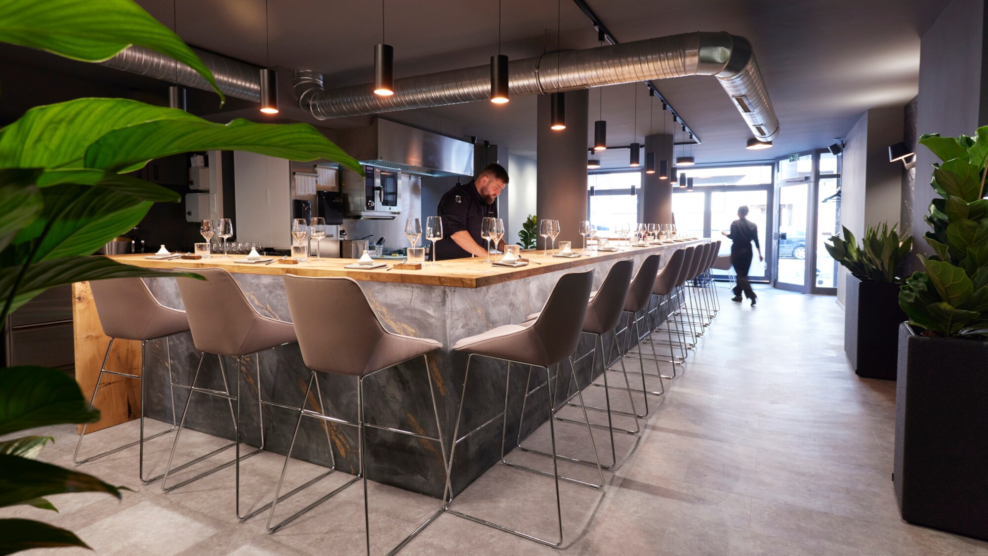 Innenraum des Restaurants Zwanzig23 in Düsseldorf, an dessen Theke Küchenchef Lukas Jakobi steht.