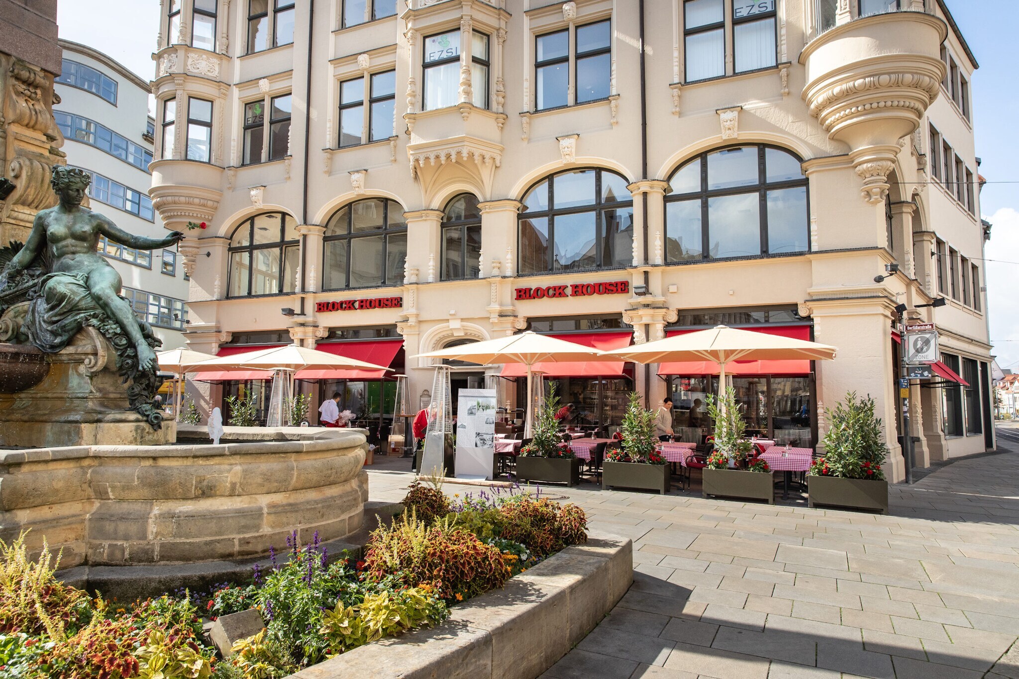 Block House Restaurant mit Außengastronomie in einem historischen Gebäude an einem Platz mit Brunnen in einer Altstadt.