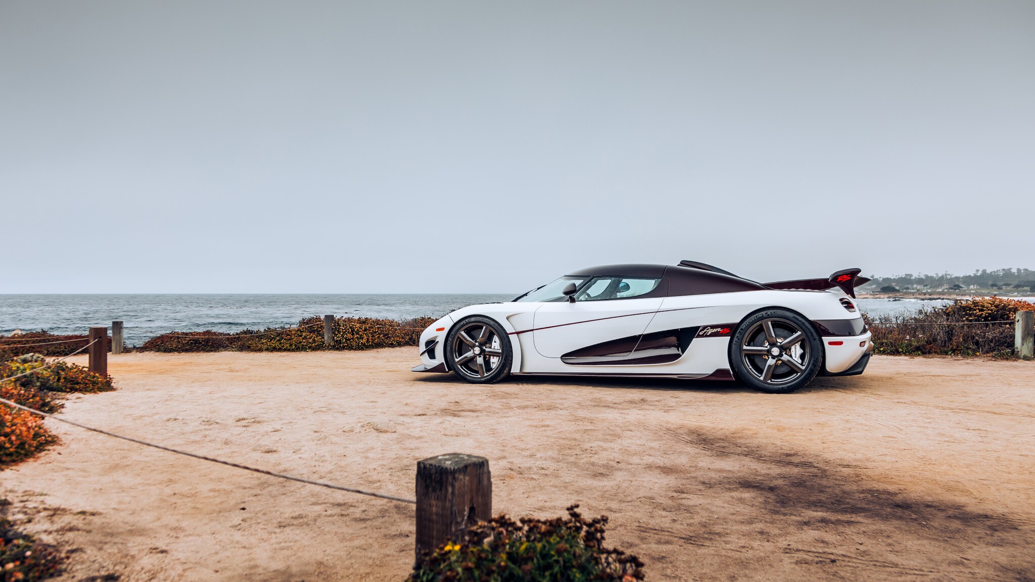 Seitenansicht eines weißen Koenigsegg Rennwagen an einer Meeresküste.