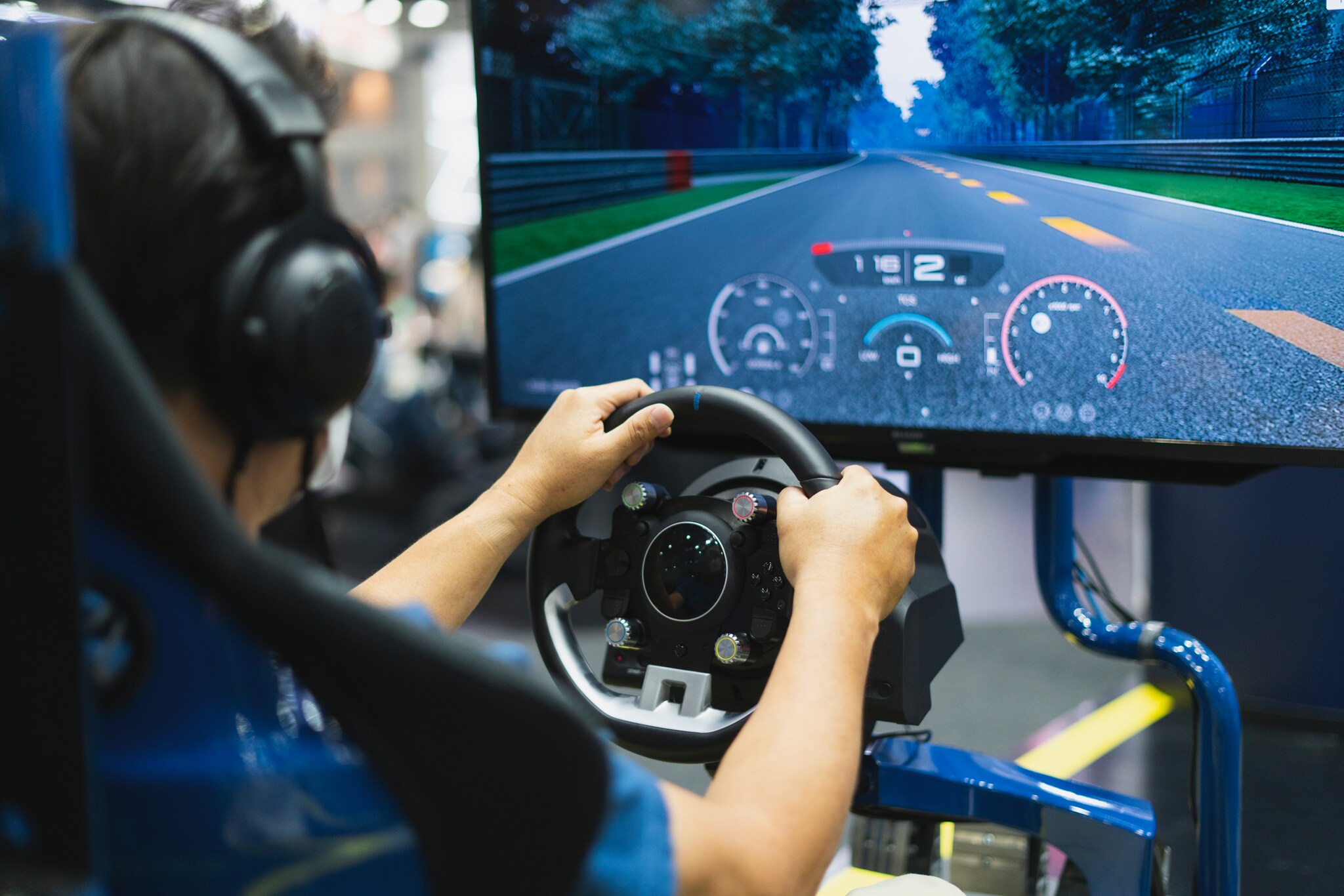 Eine Person am Lenkrad in einem Rennsimulator, im Display eine Rennstrecke.