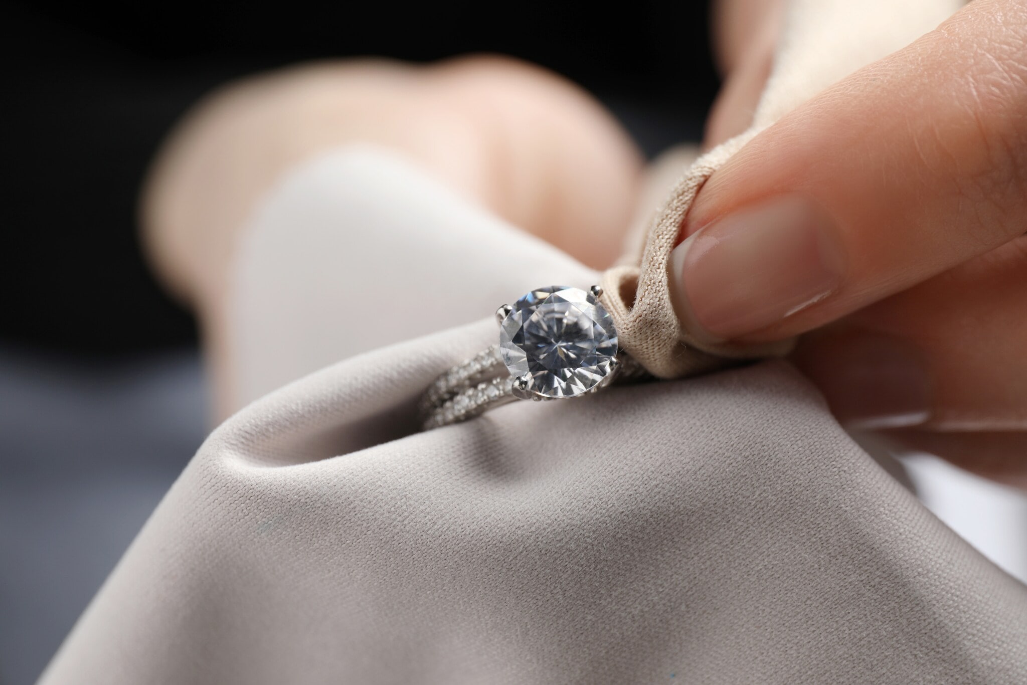 Nahaufnahme eines Diamantrings in einer Hand mit Mikrofasertuch. Nahaufnahme eines Diamantrings in einer Hand mit Mikrofasertuch.