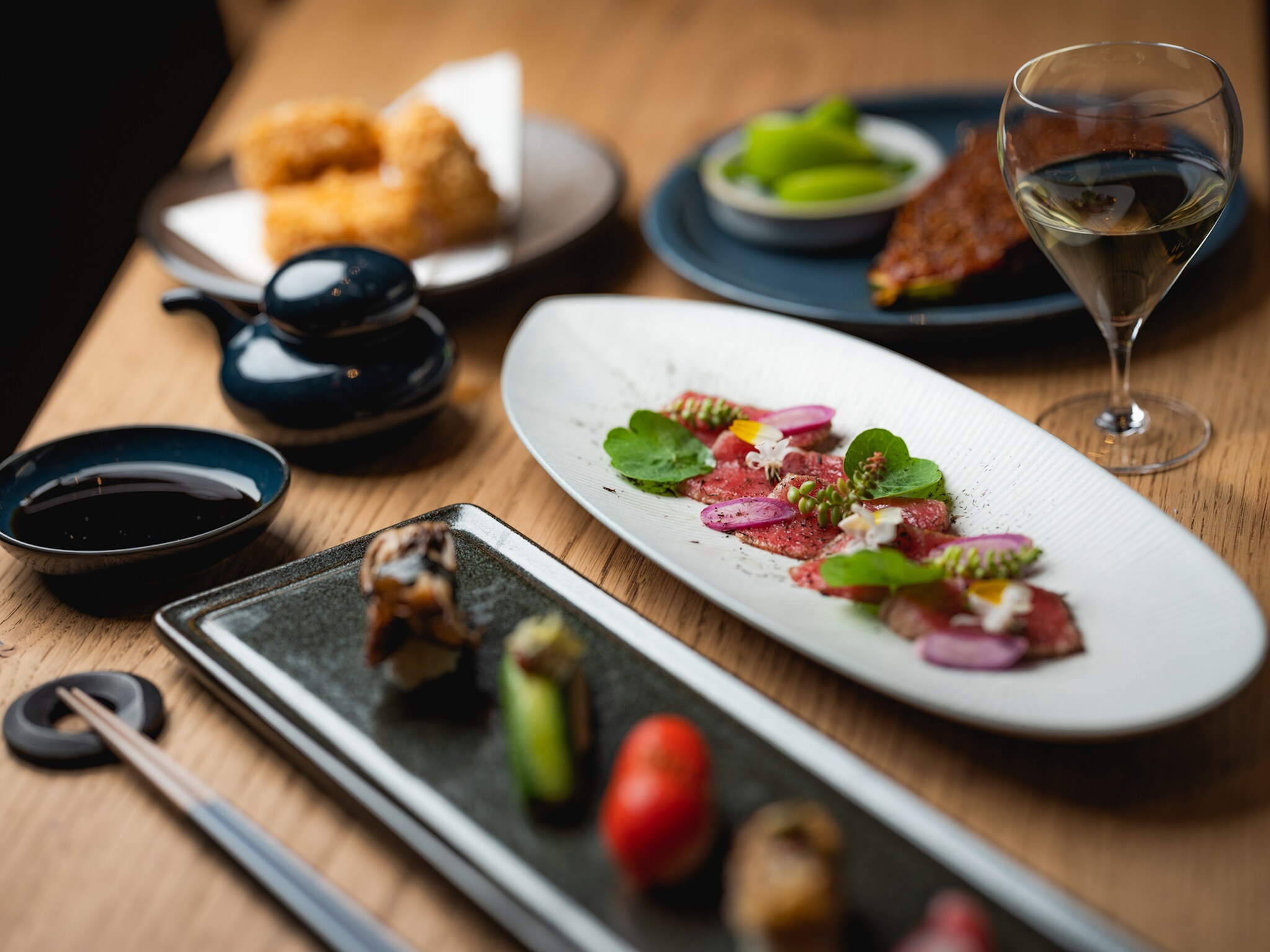 Gedeckter Holztisch mit japanischen Tapas und Sushi-Kreationen.