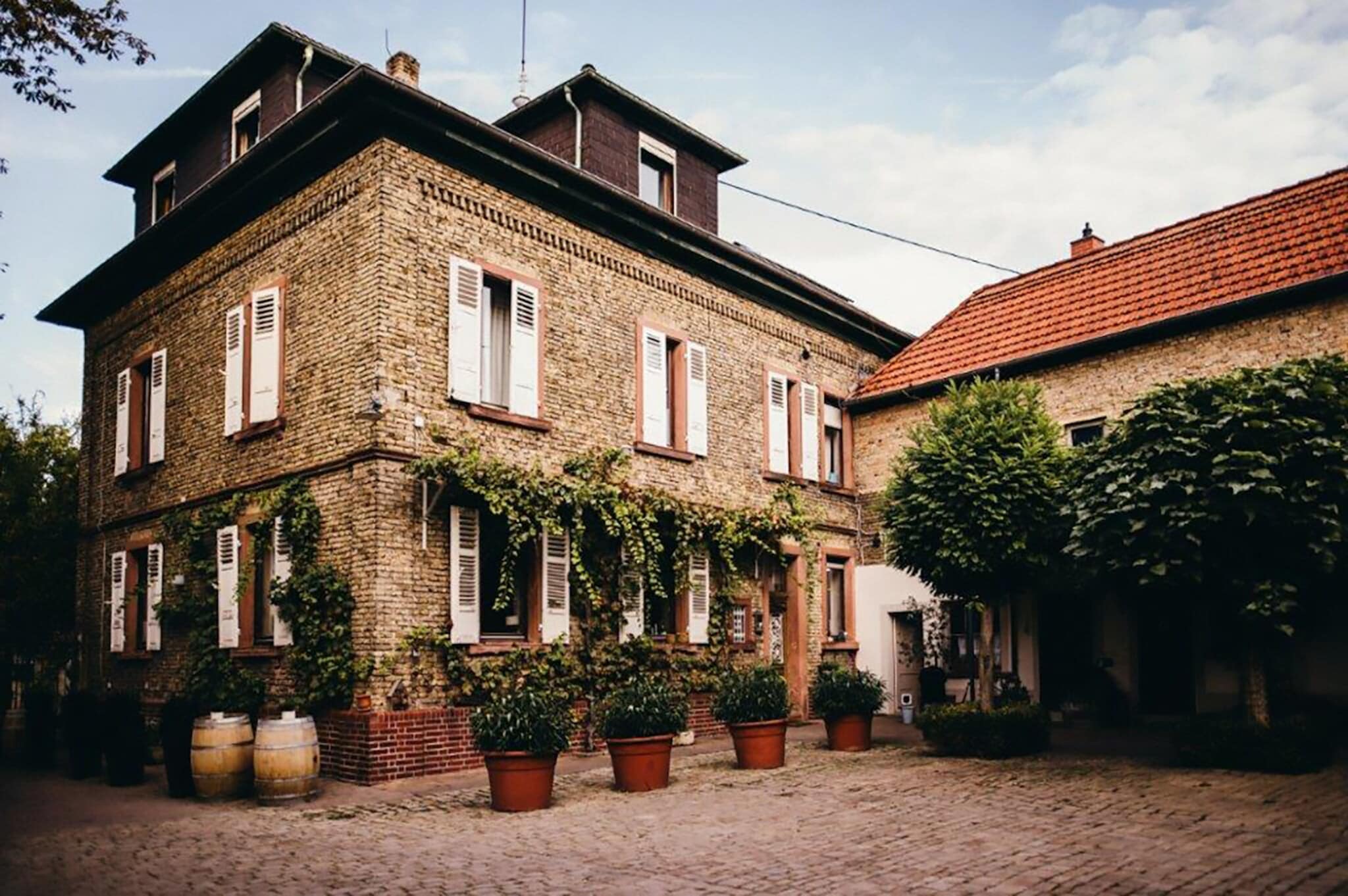 Renoviertes Gutshaus aus Backstein mit weißen Fensterläden und grünen Pflanzen. Renoviertes Gutshaus aus Backstein mit weißen Fensterläden und grünen Pflanzen.
