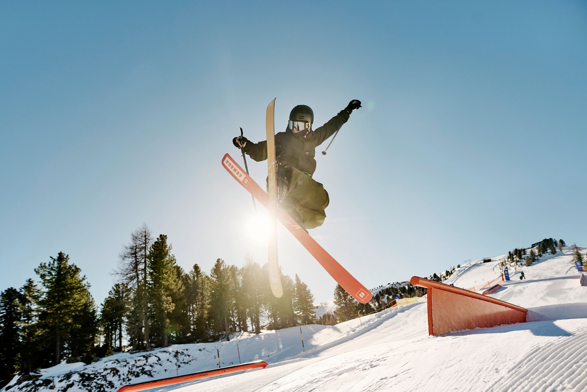 Ein Freestyle Skifahrer bei einem Sprung auf einem Parkour auf einer Skipiste.