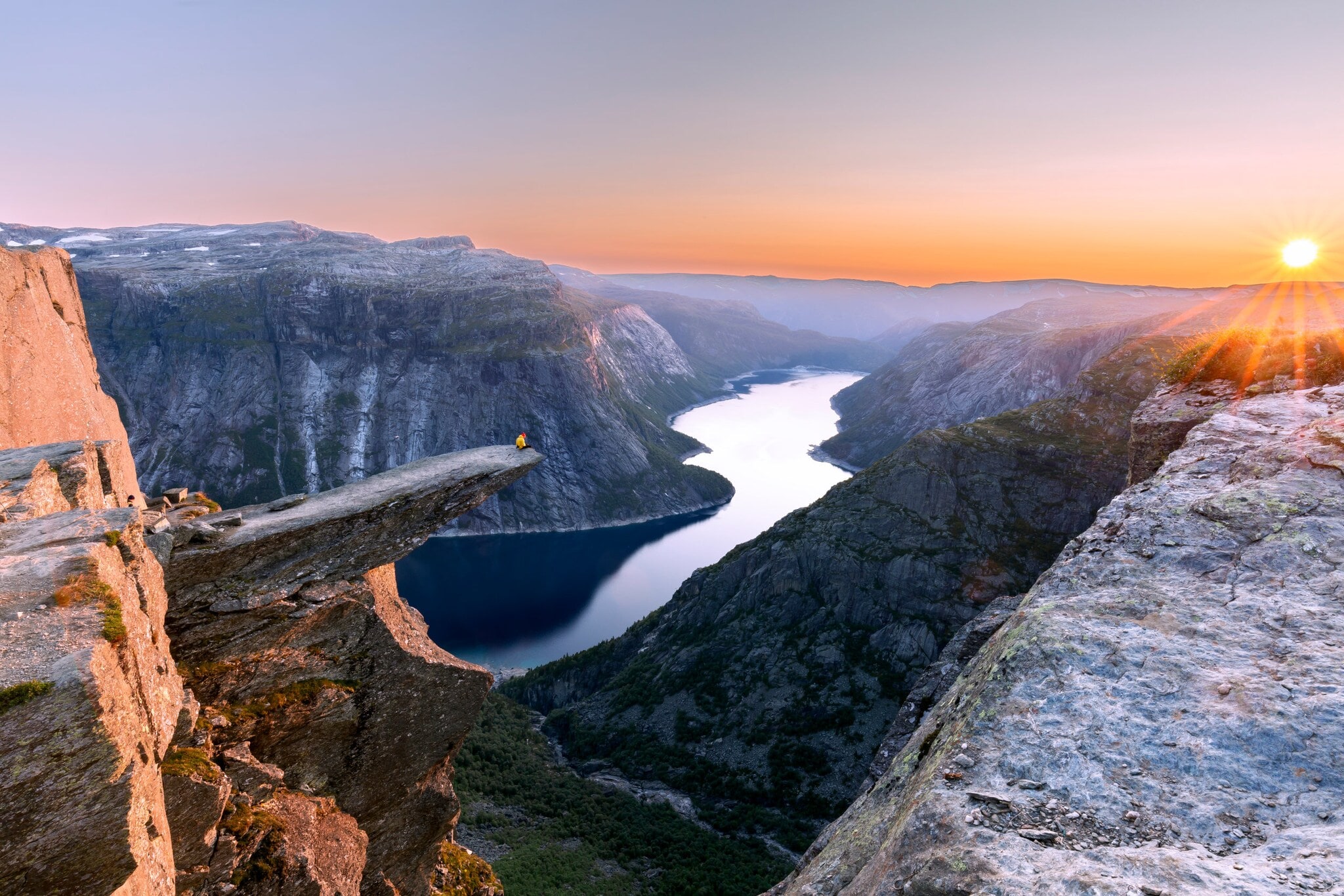 Fjordlandschaft mit Person auf einer Felsklippe bei Sonnenuntergang. Fjordlandschaft mit Person auf einer Felsklippe bei Sonnenuntergang.