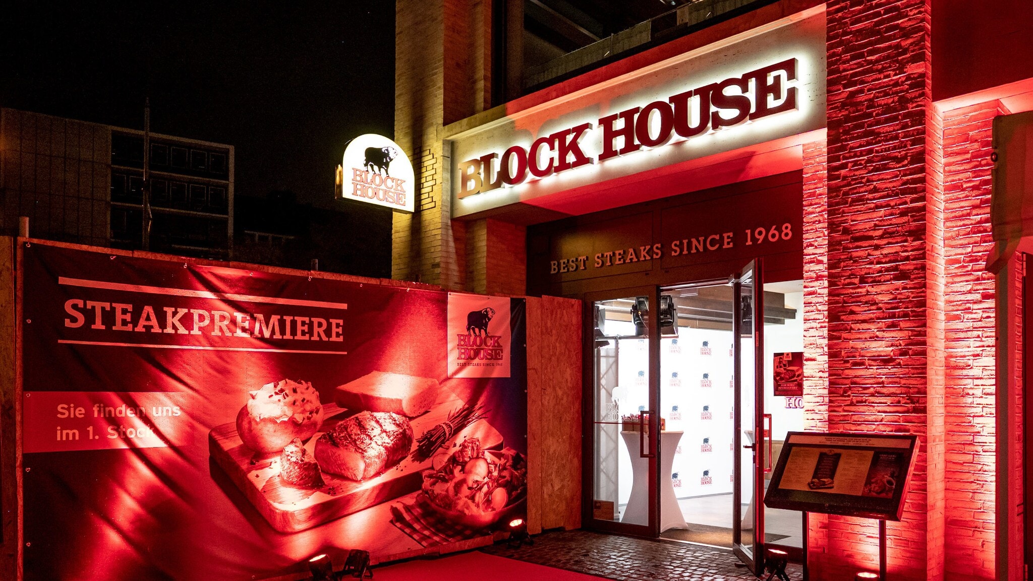 Rot beleuchteter Eingangsbereich eines BLOCK HOUSE Restaurants mit Werbebanner. Rot beleuchteter Eingangsbereich eines BLOCK HOUSE Restaurants mit Werbebanner.