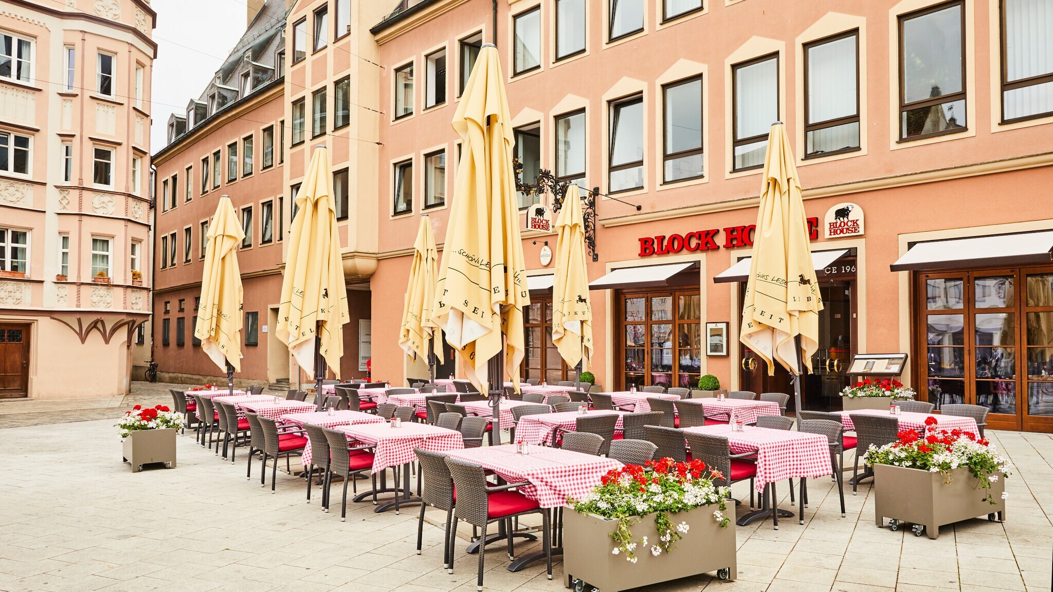 Block House Restaurant mit Außengastronomie auf einem Platz in einer Altstadt.