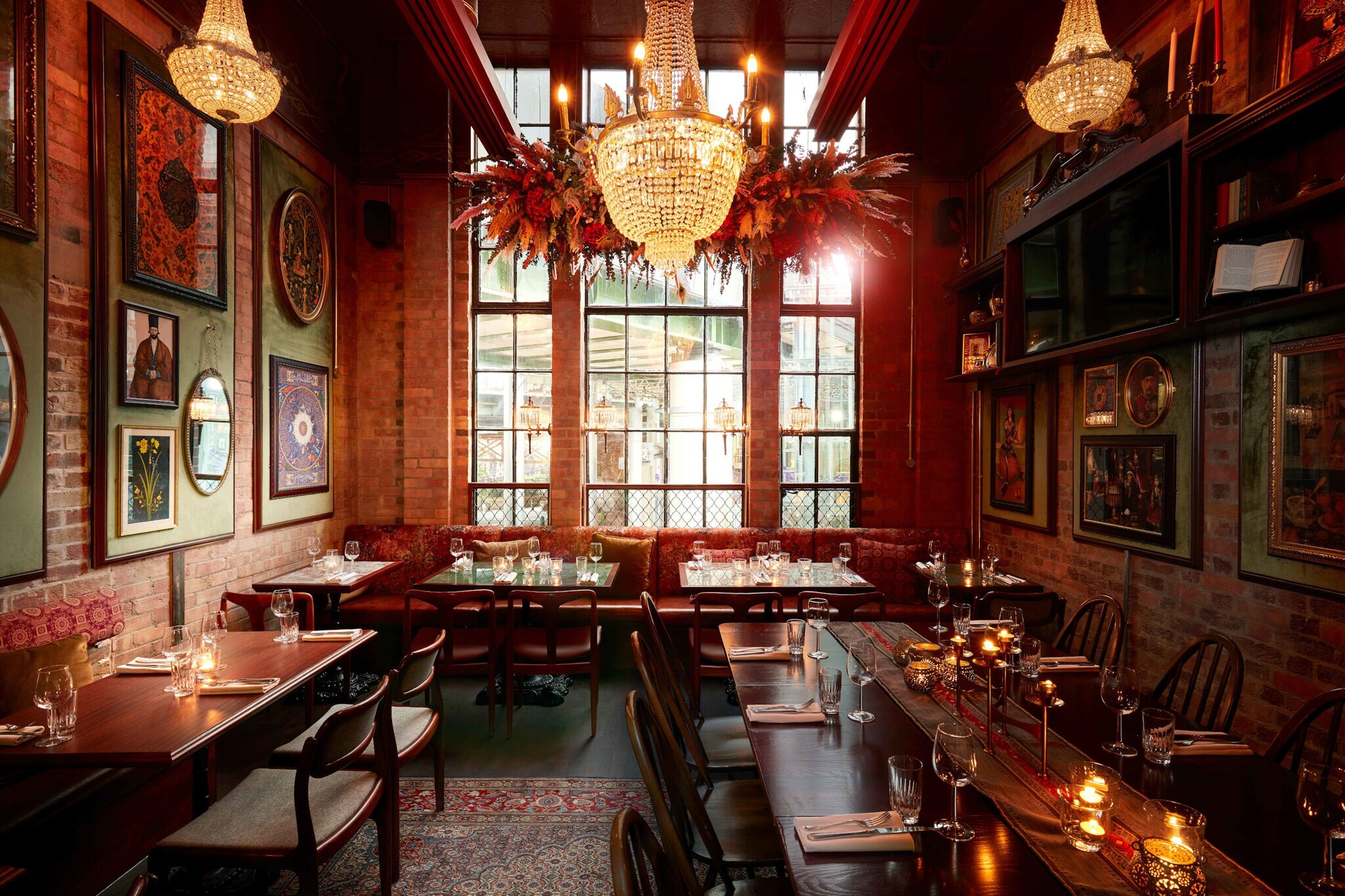 Eingedeckte Holztische auf einem Perserteppich im Speisesaal eines orientalischen Restaurants mit Backsteinwänden und warmer Beleuchtung.