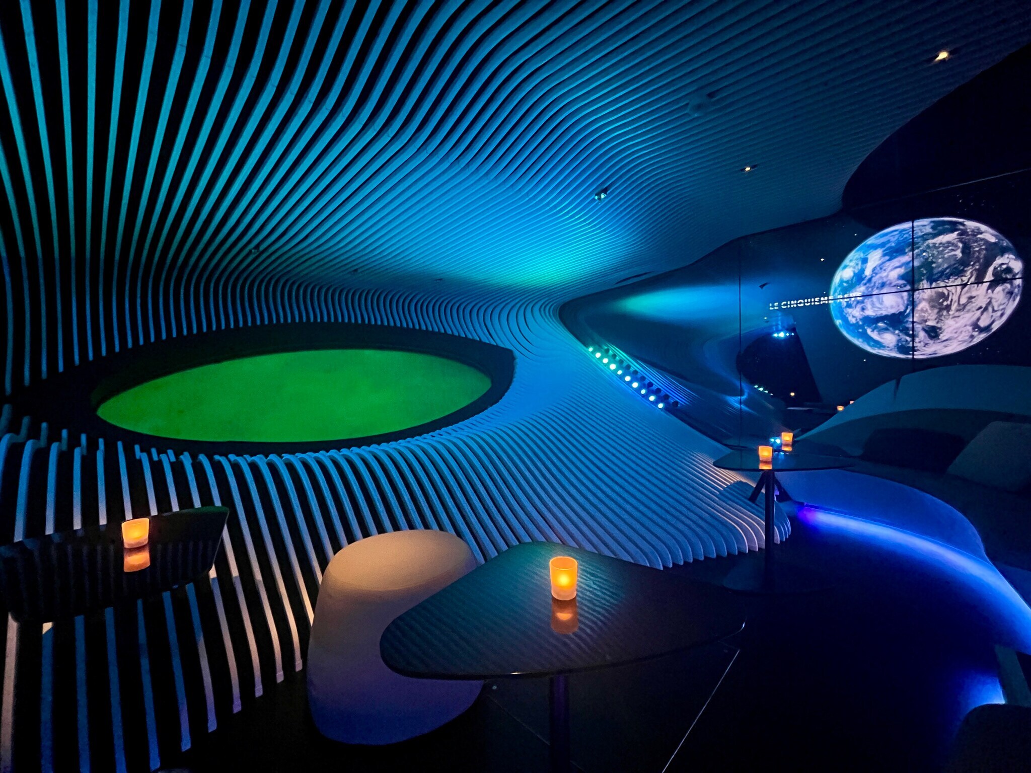 Das Bild zeigt eine Lounge an Bord des Schiffes Le Bellot. Auf mehreren Tischen stehen Kerzen. Die Wände sind mit einem linienförmigen Muster verziert.