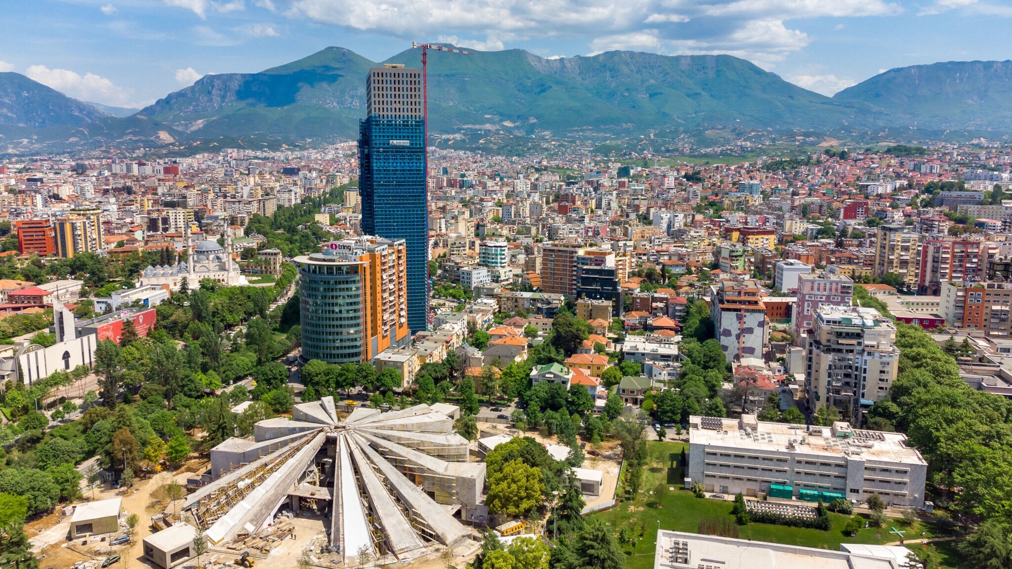 Luftaufnahme der albanischen Hauptstadt Tirana mit Bergen im Hintergrund.