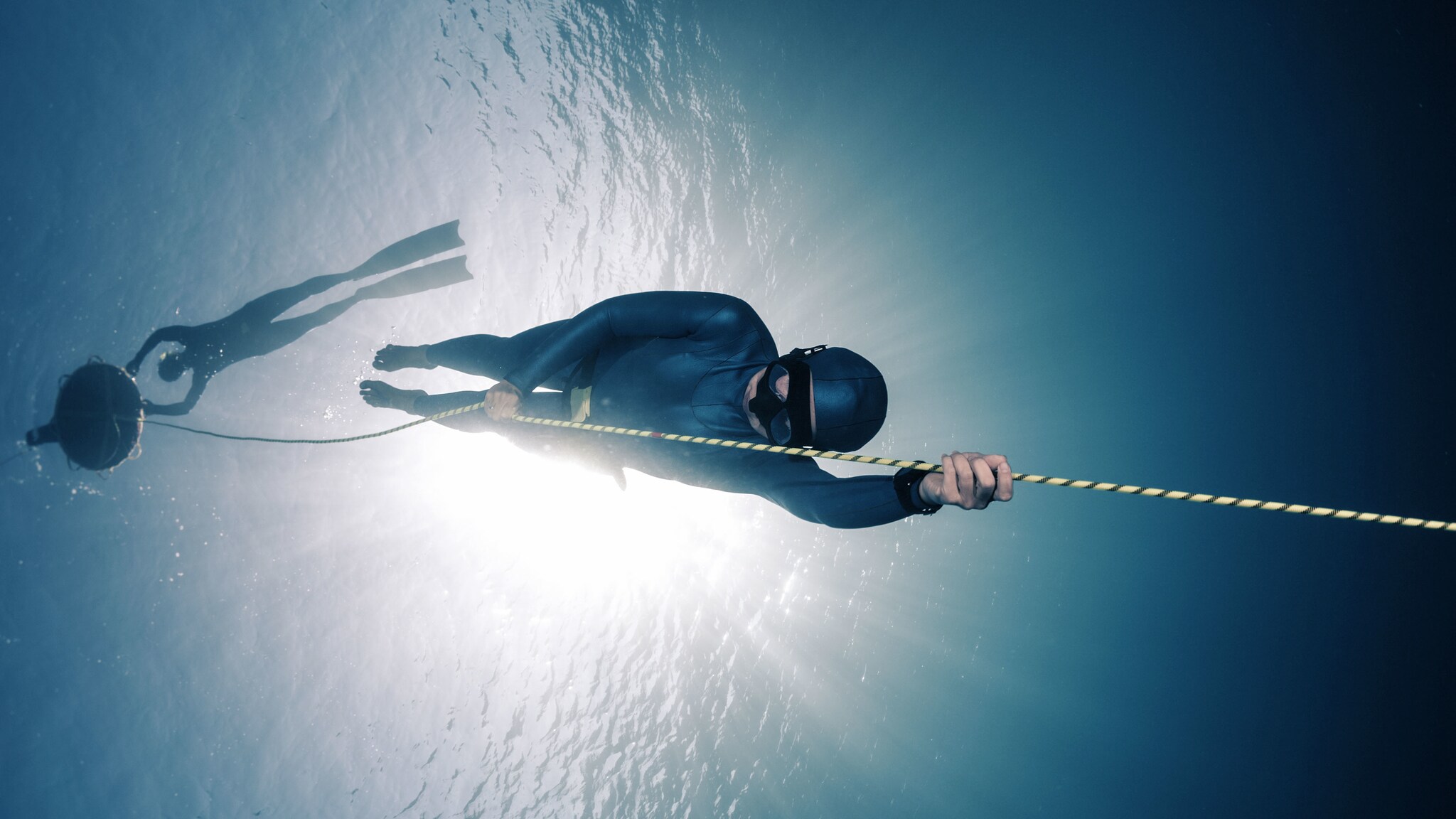 Ein Apnoetaucher hält sich unter Wasser an einem Seil fest.