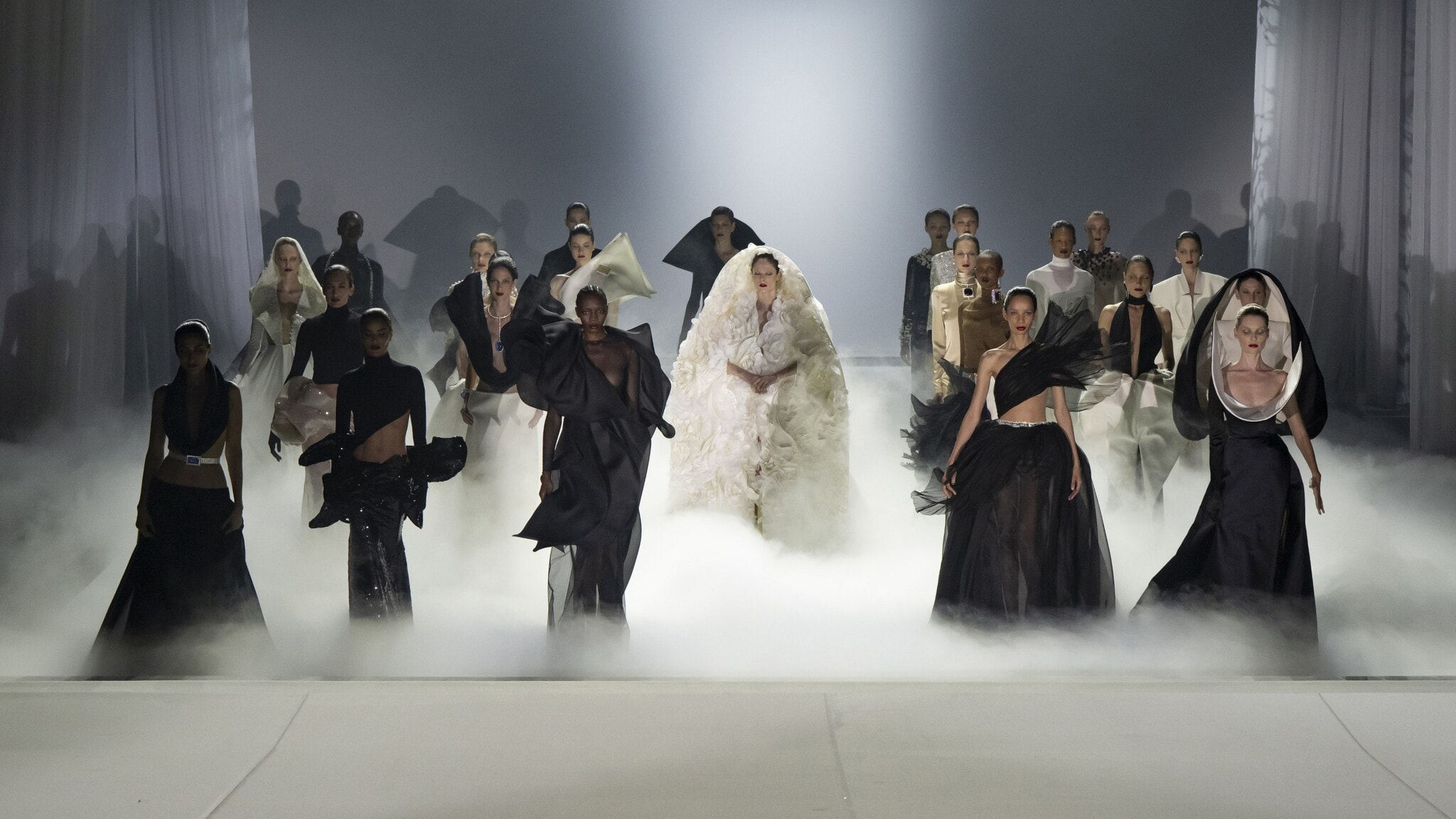 Weibliche Models in schwarz-weißer Haute Couture Kleidung, aufgereiht bei einer Modenschau. Weibliche Models in schwarz-weißer Haute Couture Kleidung, aufgereiht bei einer Modenschau.