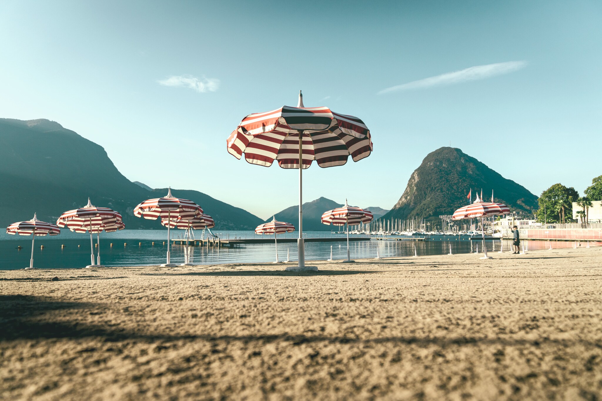 Sandstrand mit rot-weiß gestreiften Sonnenschirmen.