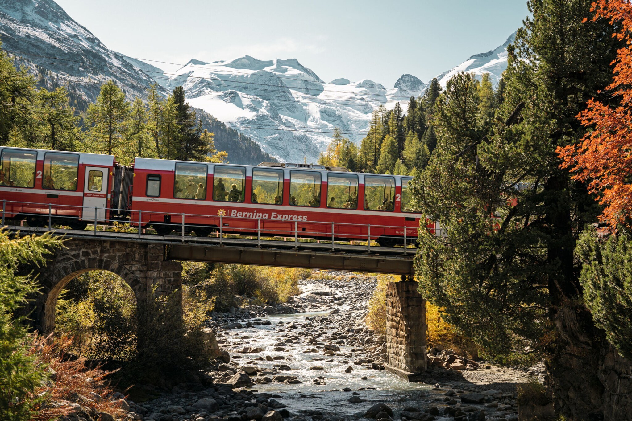 in roter Panoramazug auf einer Brücke in einer Berglandschaft.
