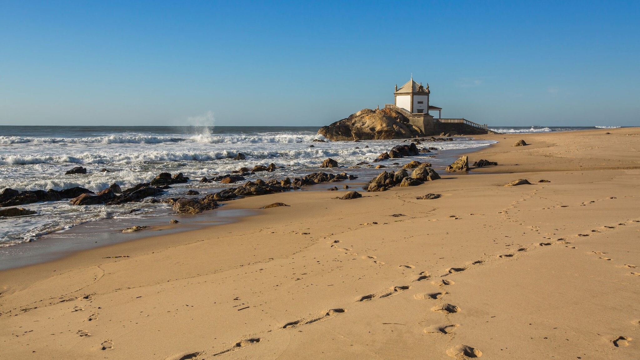 Praia da Miramar in Portugal mit Felsen, auf dem eine kleine Kapelle steht. Praia da Miramar in Portugal mit Felsen, auf dem eine kleine Kapelle steht.