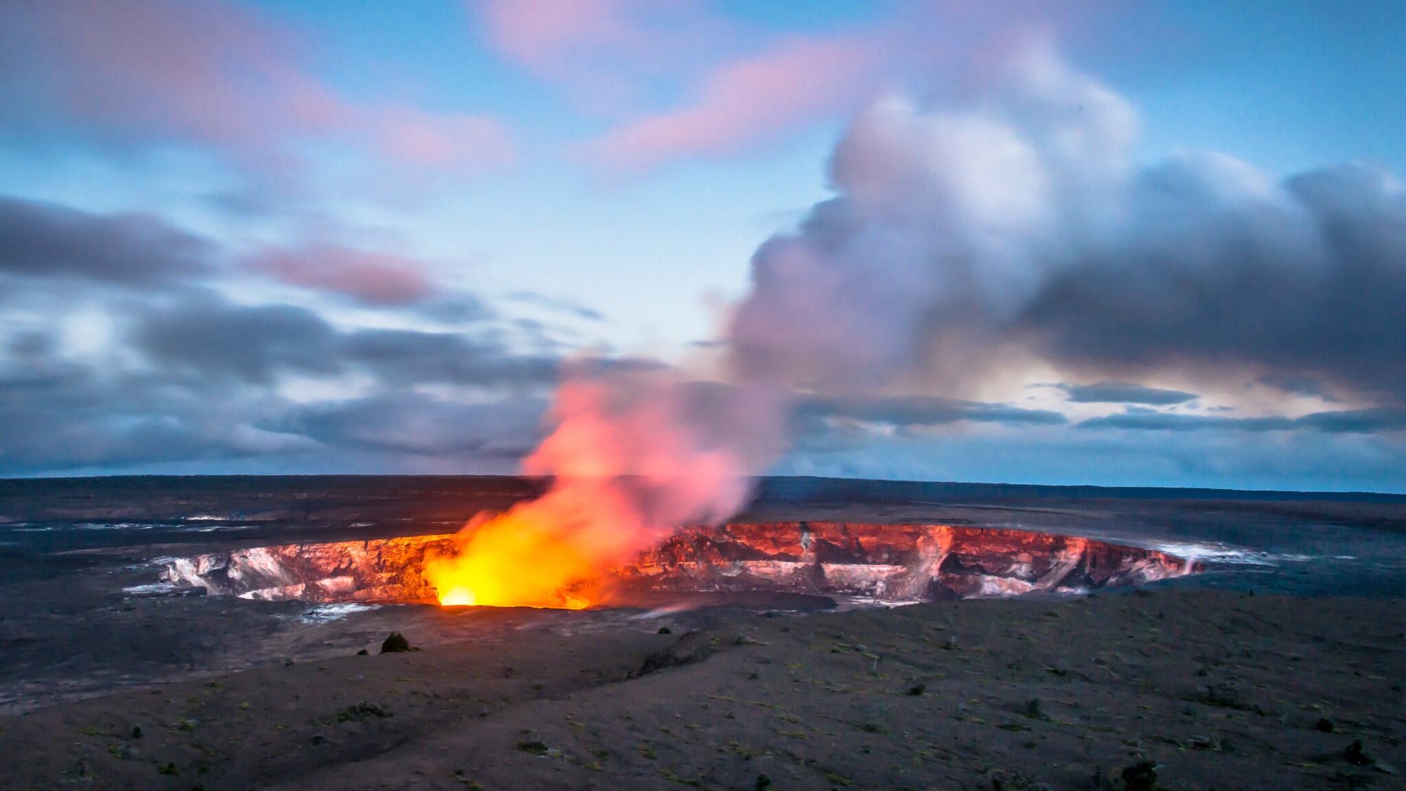 Vulkankrater auf ebener Fläche, aus dem Feuerwolken emporsteigen.