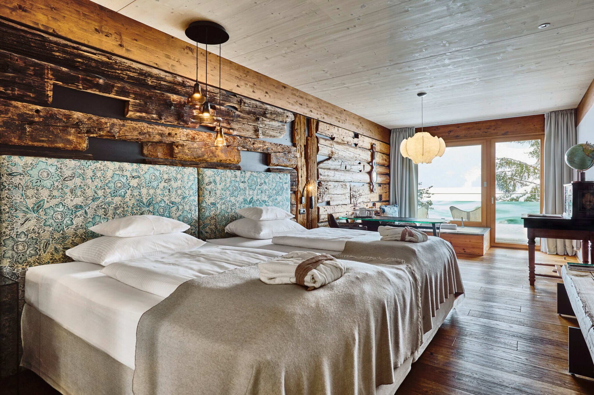 Helles Hotelzimmer mit Holzverkleidung im Chalet-Stil und zwei Doppelbetten.