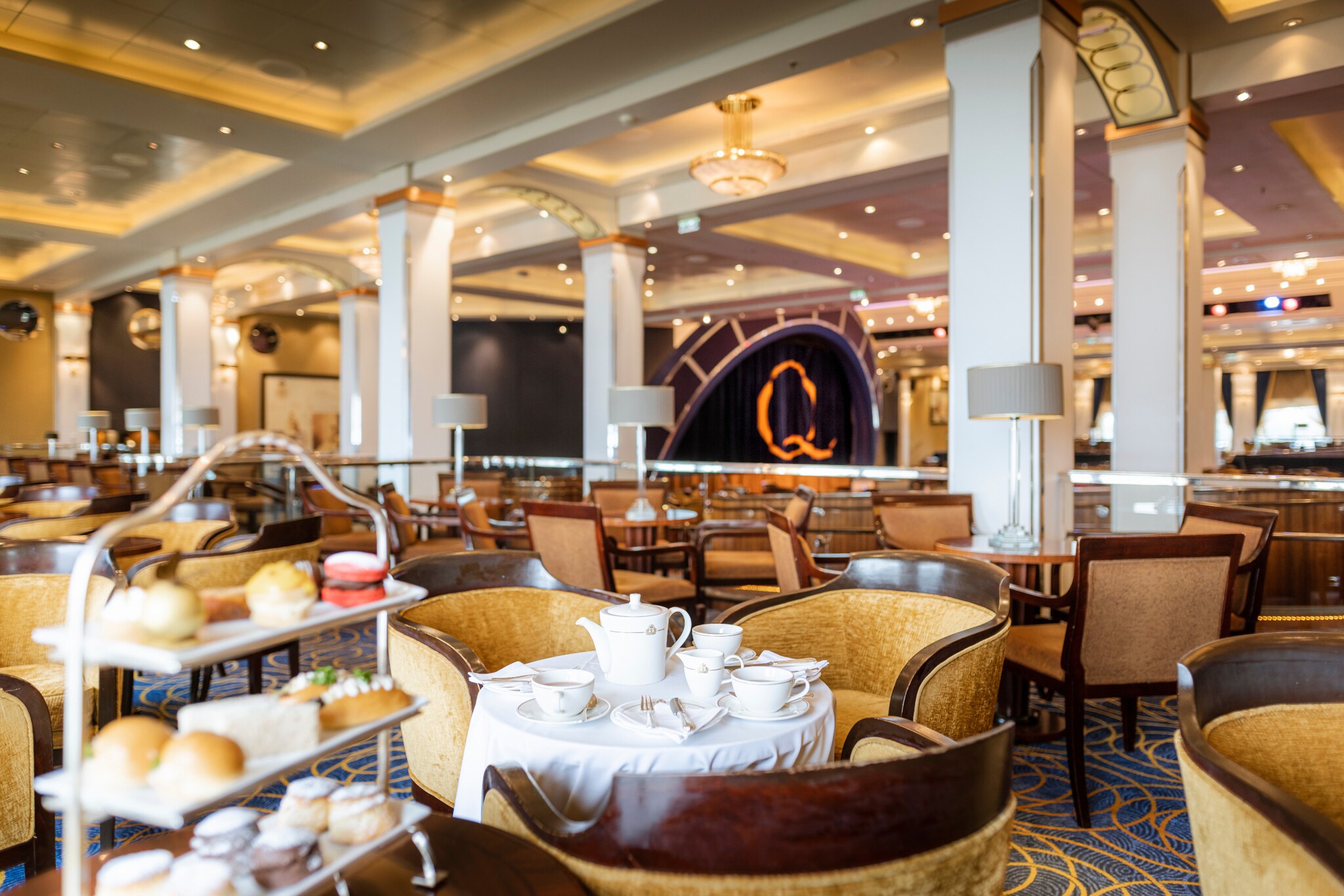 Ein für den Afternoon Tea eingedeckter Tisch in einem eleganten Saal mit Tischen und Polstermöbeln.