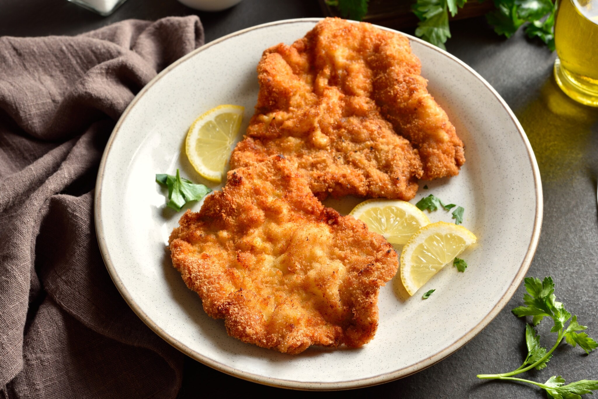 Ein Wiener Schnitzel auf einem Teller mit Zitronenscheiben. Ein Wiener Schnitzel auf einem Teller mit Zitronenscheiben.