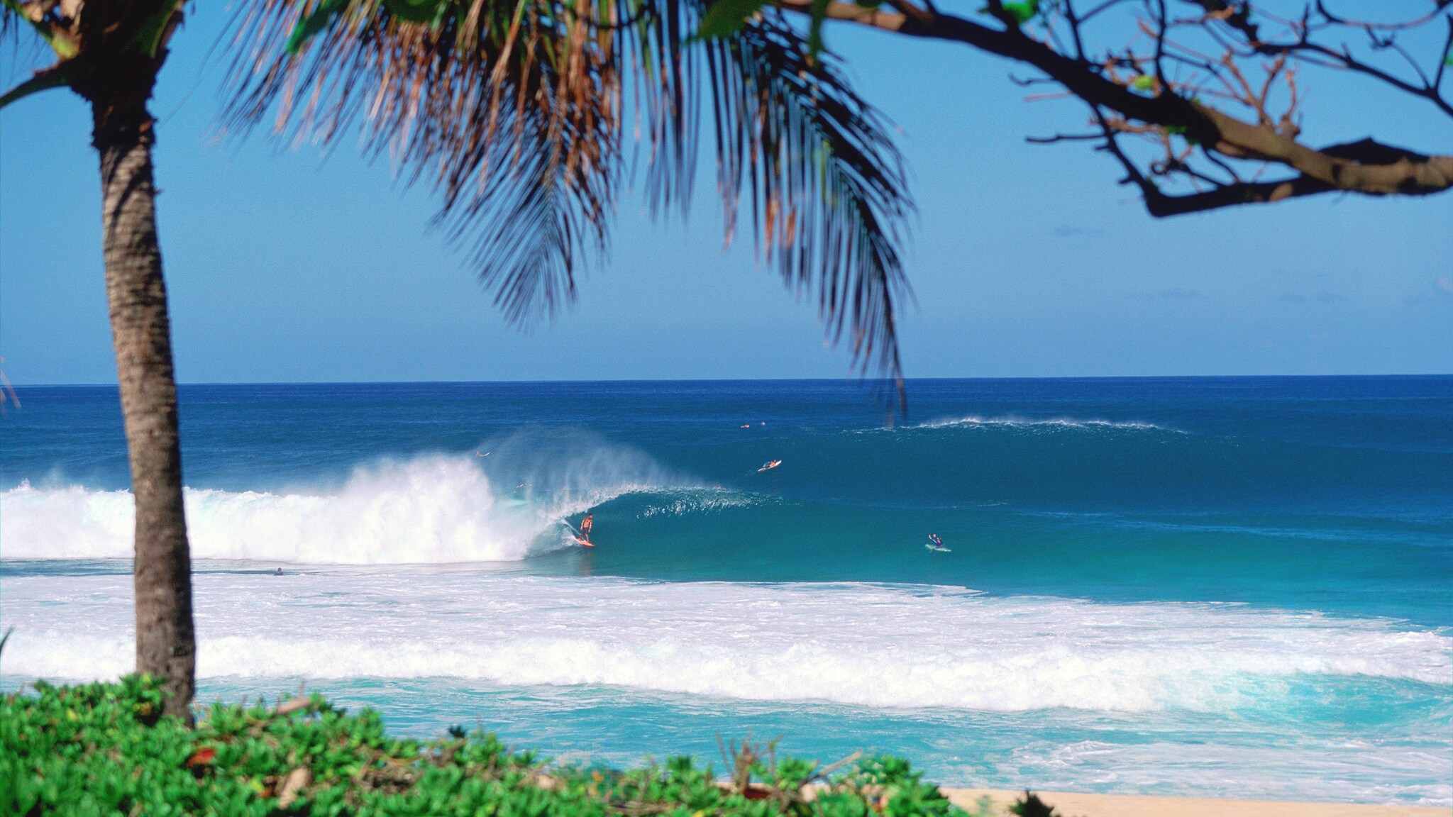 Strandabschnitt mit Surfenden im Meer.