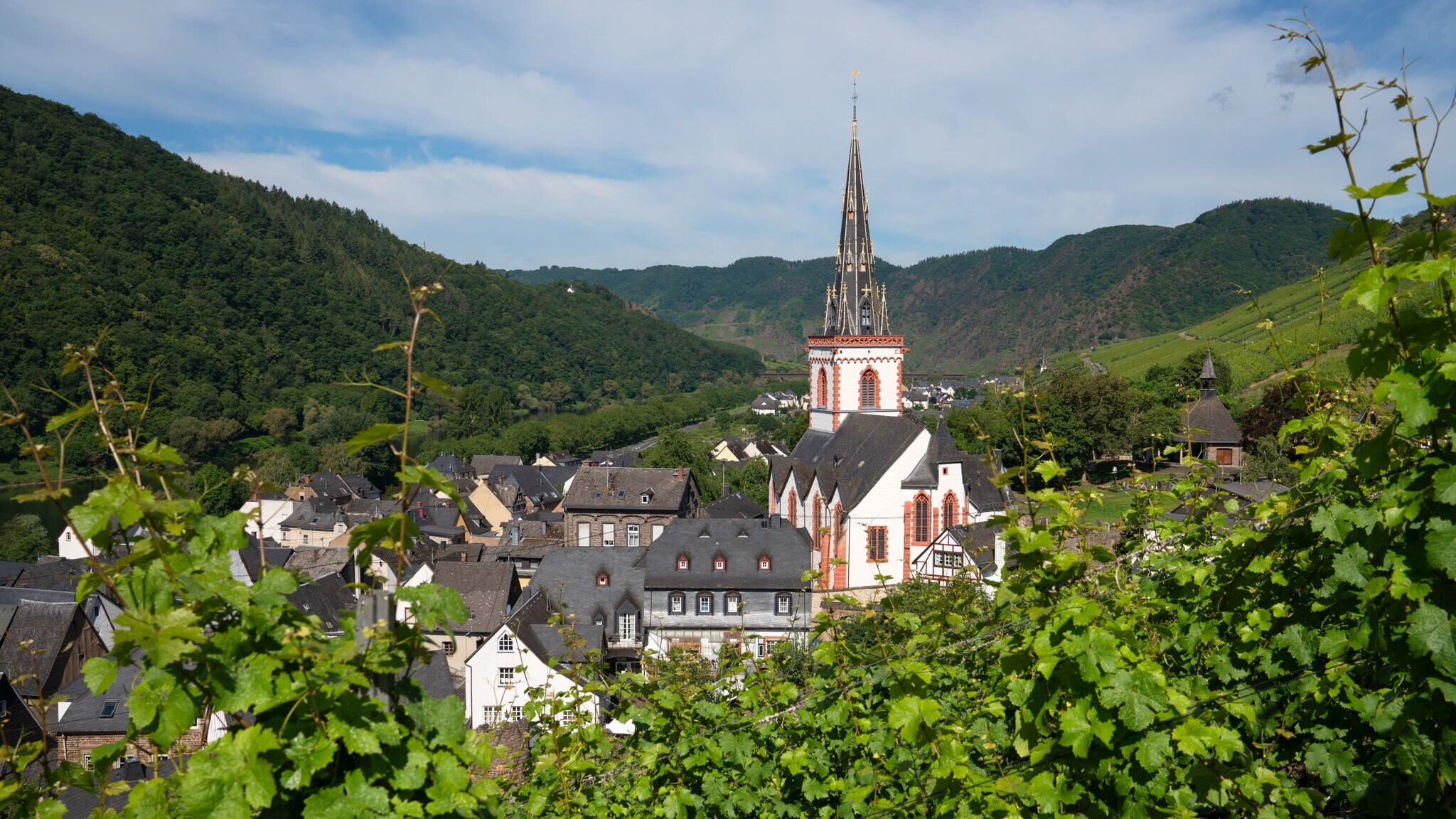 Ort Ediger-Eller an der Mosel mit Kirche und grüner Landschaft im Hintergrund. Ort Ediger-Eller an der Mosel mit Kirche und grüner Landschaft im Hintergrund.