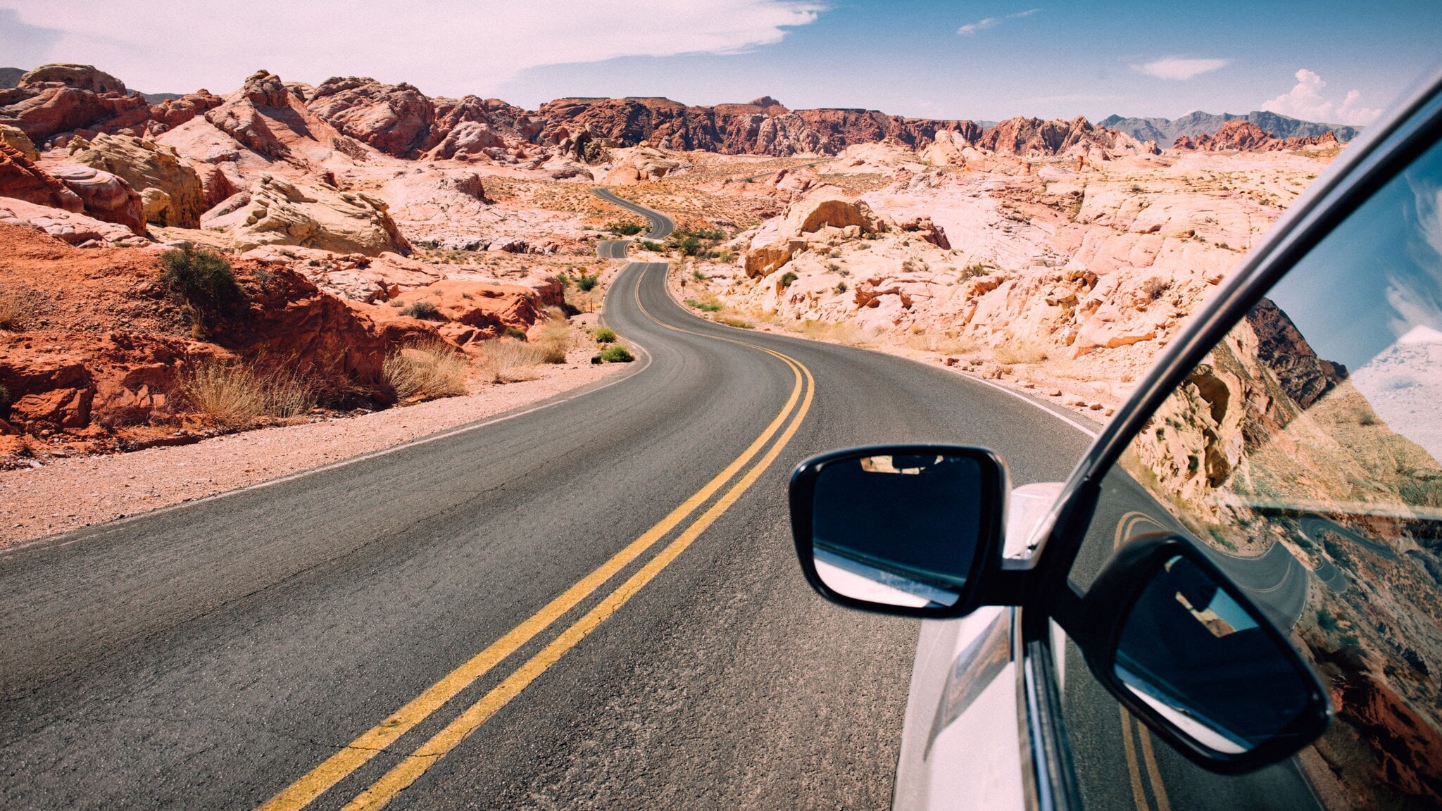 Seitenspiegel eines Autos auf einer US-amerikanischen Autobahn in einer felsigen Wüstenlandschaft. Seitenspiegel eines Autos auf einer US-amerikanischen Autobahn in einer felsigen Wüstenlandschaft.