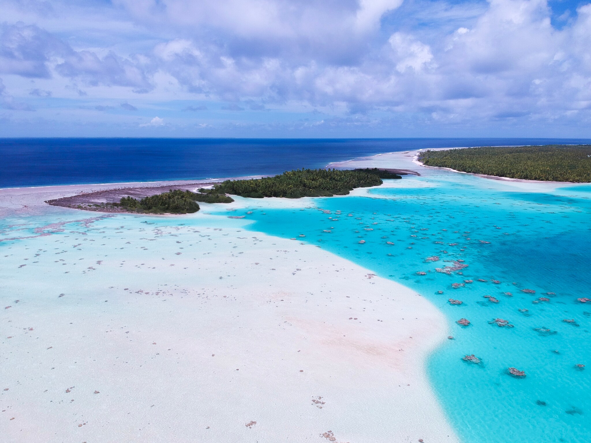 Kleine, flache Inseln mit grüner Vegetation, umgeben von Lagunenlandschaft.