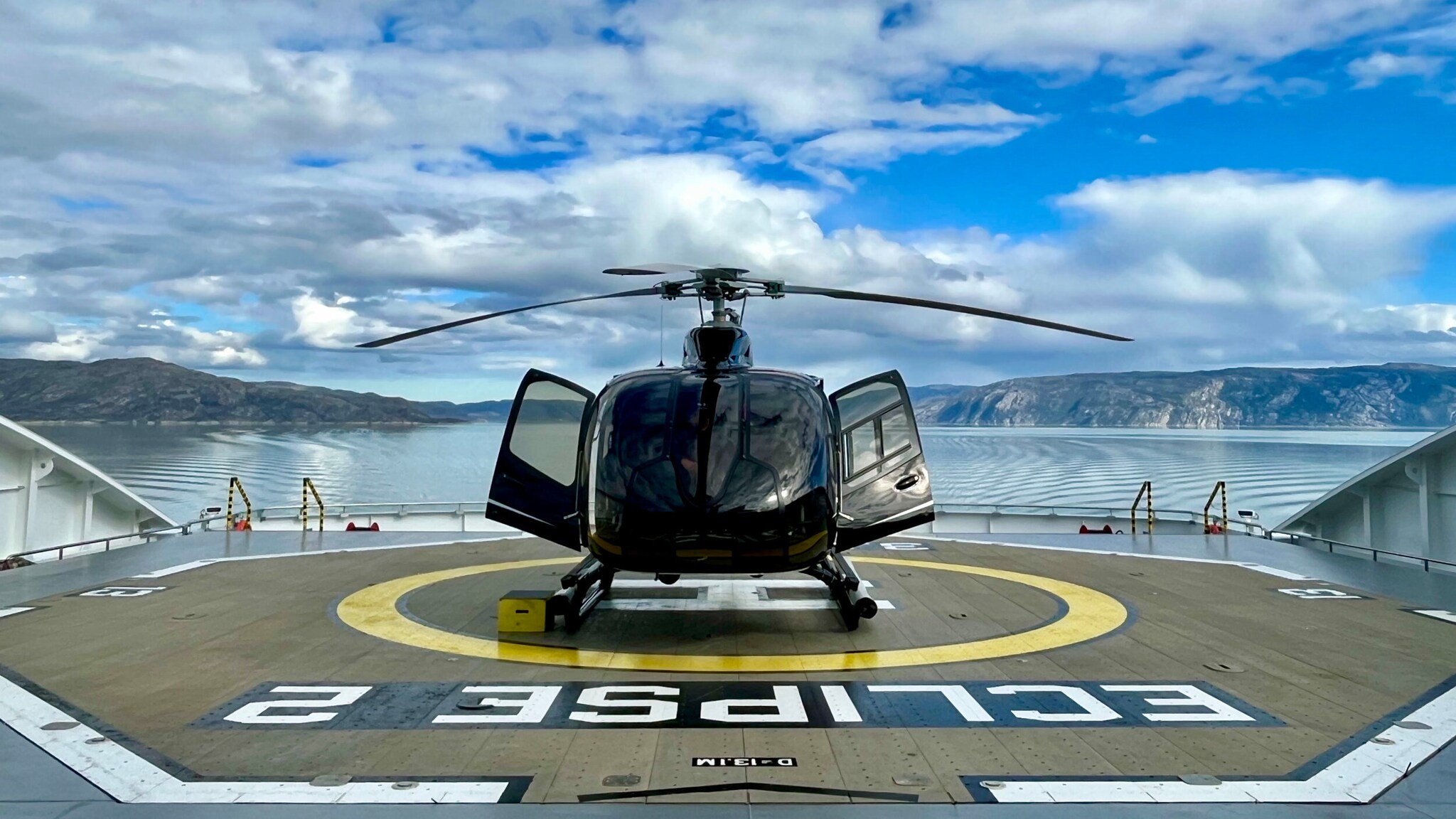 Das Bild zeigt einen der beiden Hubschrauber der Scenic Eclipse II. Im Hintergrund sind blauer Himmel und weiße Wolken zu sehen.