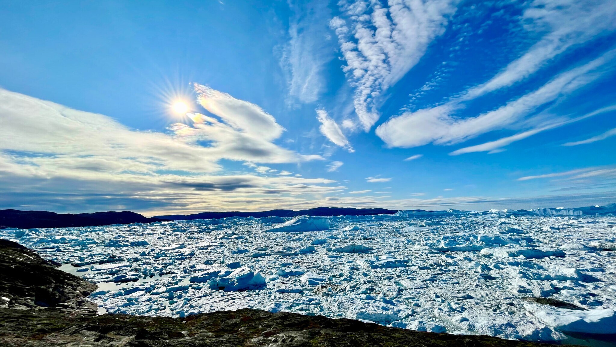 Das Bild zeigt einen komplett mit kleinen und größeren Eisbergen bedeckten Fjord.