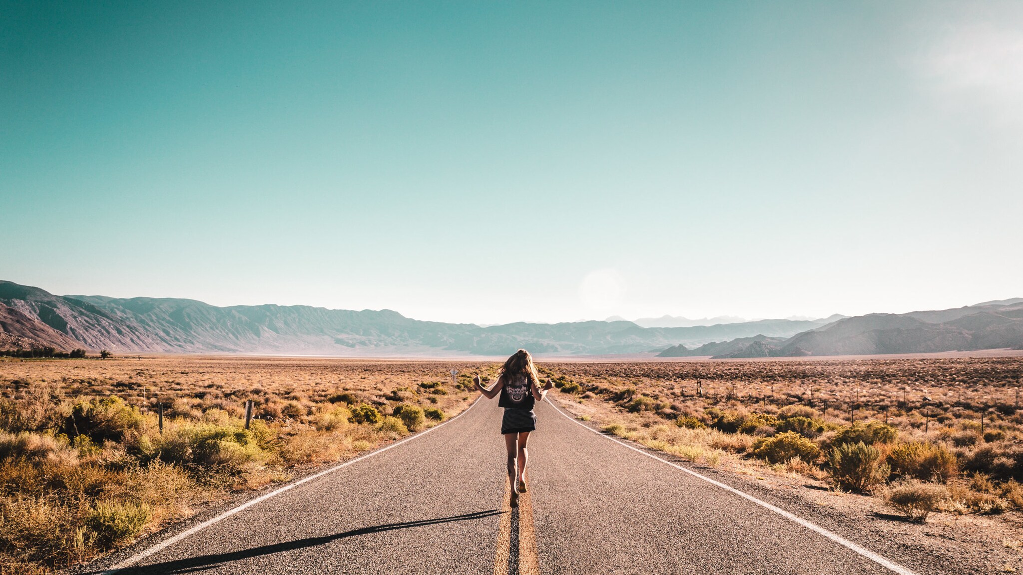 Rückansicht einer Frau, die auf einer Straße in den USA läuft. Rückansicht einer Frau, die auf einer Straße in den USA läuft.
